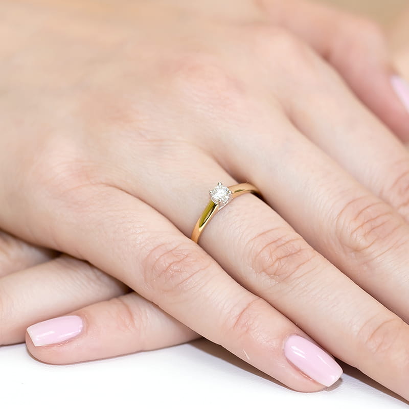 W0239.Z3.LDW.01_4 Złoty pierścionek z diamentem na palcu dłoni z różowym manicure.