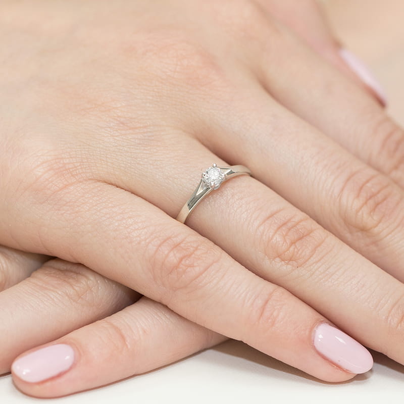 W0240.B3.DIW.01_4 Srebrny pierścionek z diamentem na palcu z różowymi paznokciami.