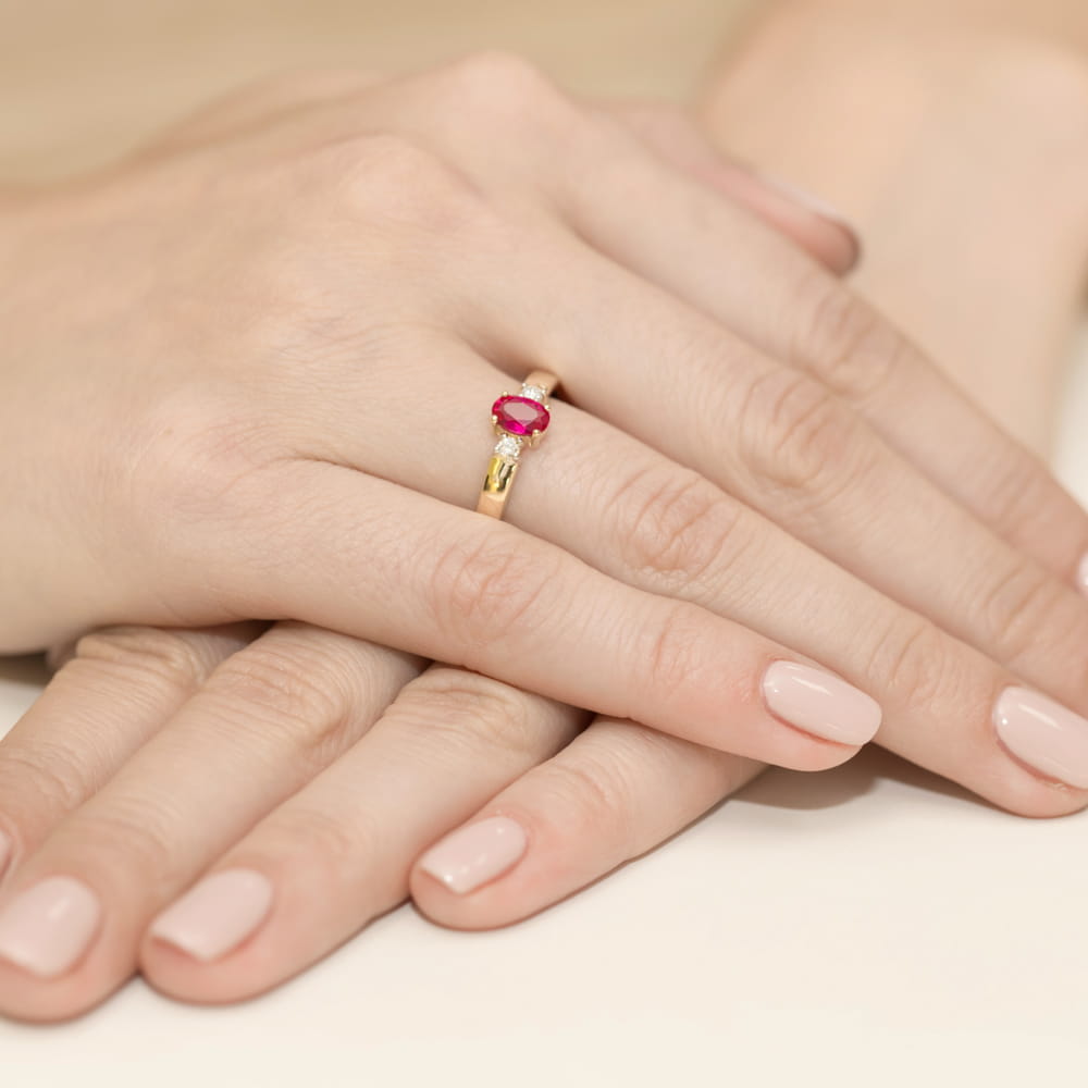 W0264.Z3.RUR.01_4 Złoty pierścionek z rubinem na palcu, dłonie z zadbanymi paznokciami w jasnym kolorze.