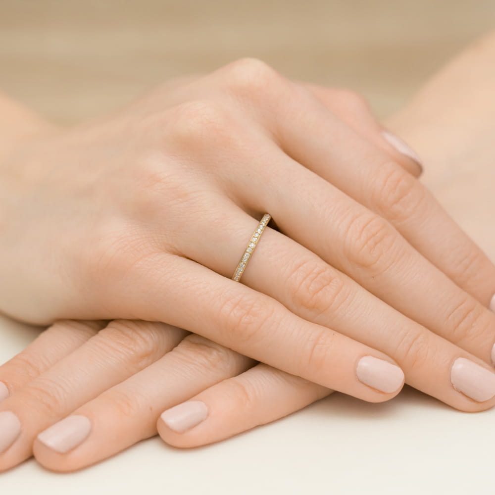 W0306.Z3.LDW.01_4 Złoty pierścionek z diamentami na palcu kobiety, ręce z delikatnym manicure w neutralnym kolorze.