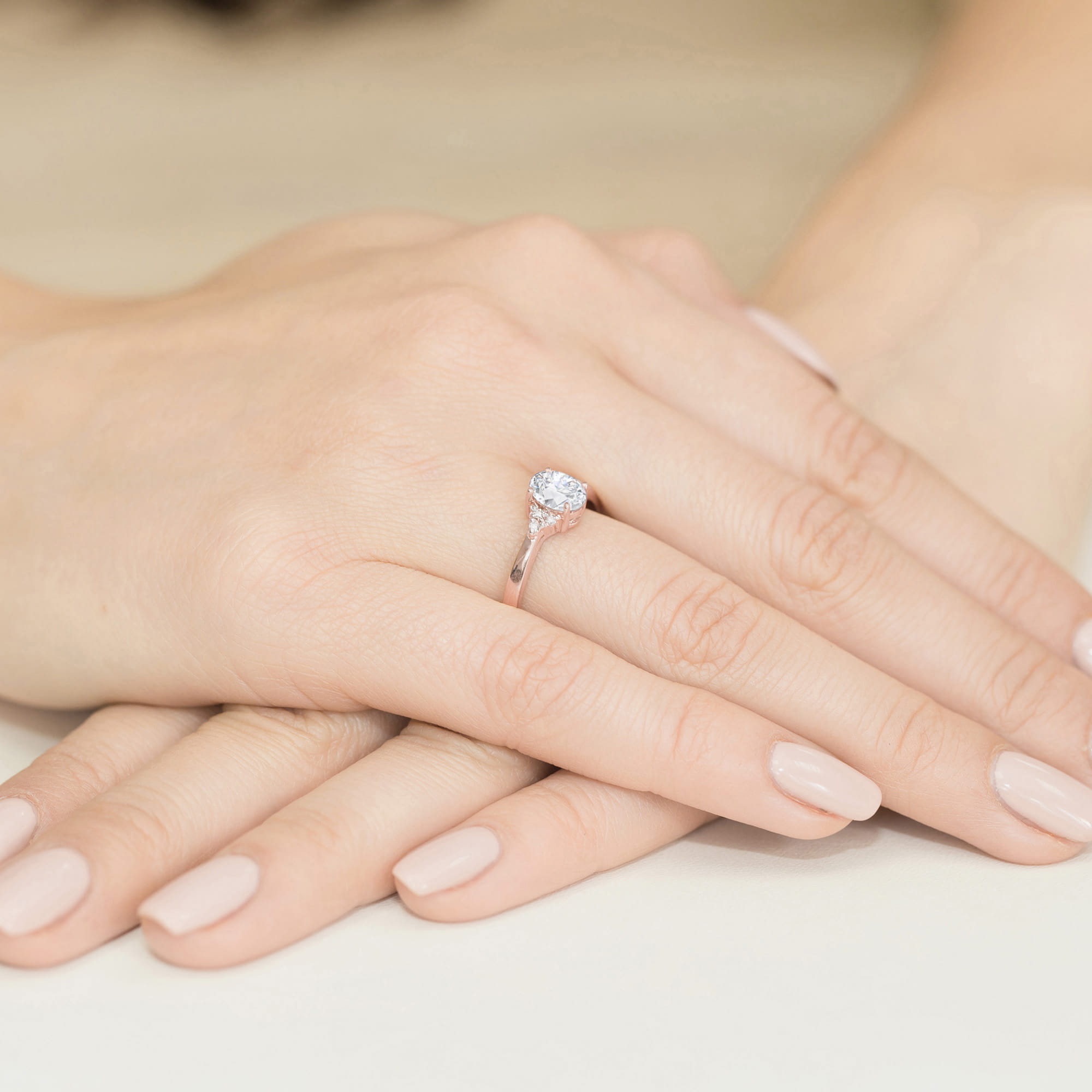 W0308.R3.LDW.01_4 Na dłoni z delikatnym manicure znajduje się pierścionek z dużym, błyszczącym diamentem.