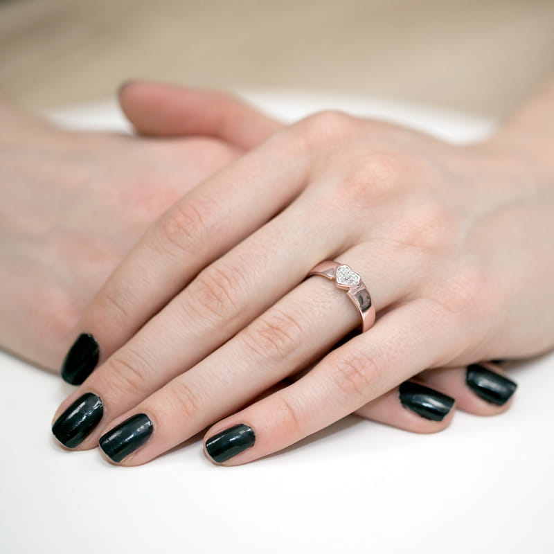 W0314.R3.DIW.01_4 Dwie ręce z ciemnym manicure, jedna z pierścionkiem w kształcie serca na palcu.