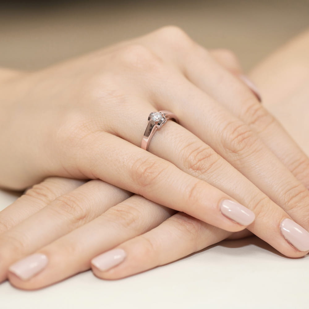 W0320.R3.DIW.07_4 Dwie dłonie z delikatnym manicure, jedna z pierścionkiem z diamentem na palcu.