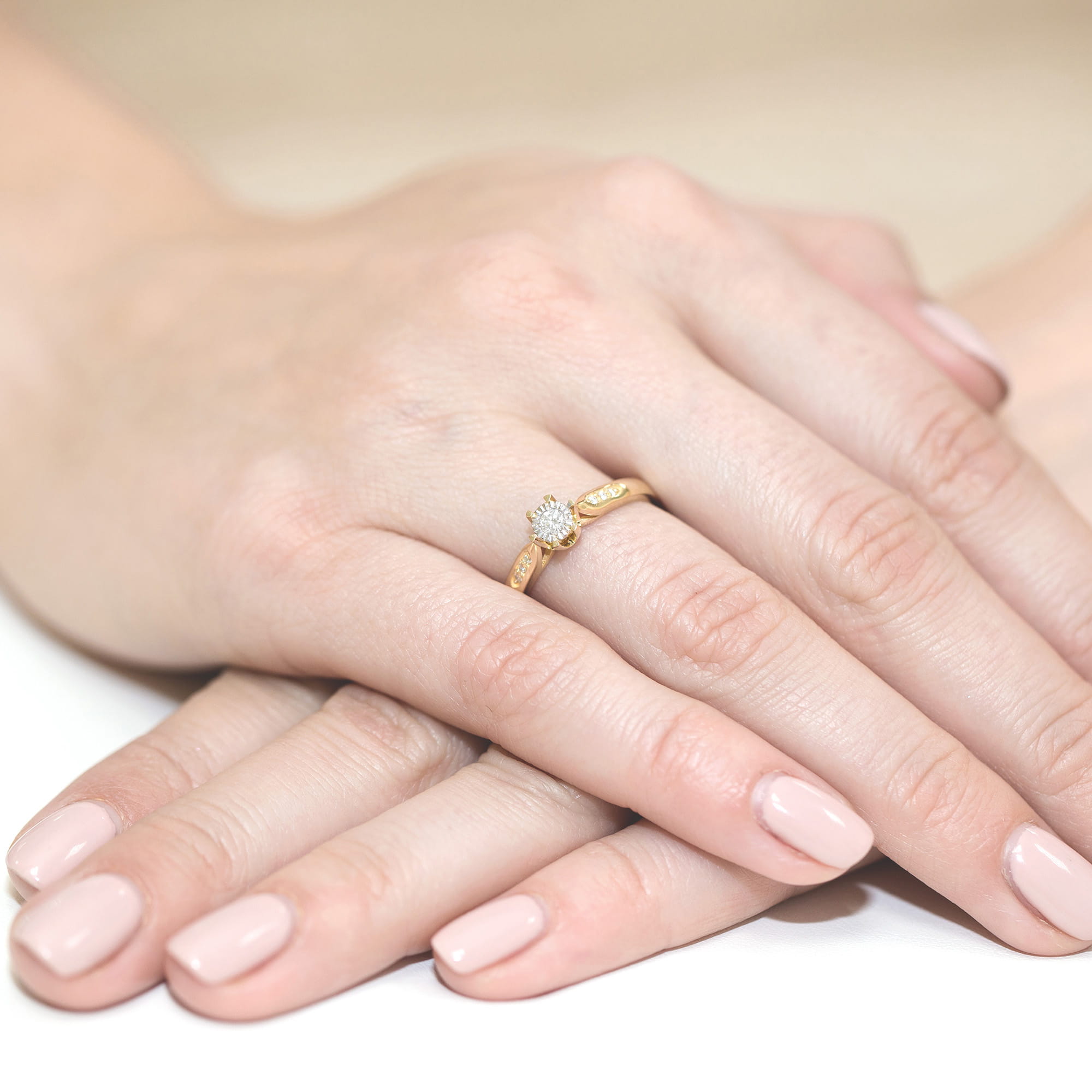 W0328.Z3.LDW.01_4 Na dłoni z delikatnym manicure znajduje się złoty pierścionek z diamentem.