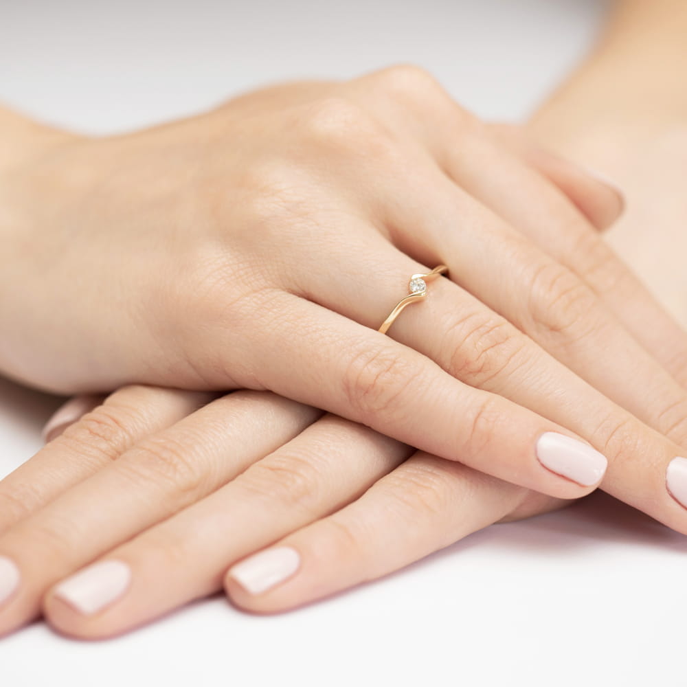 W0332.Z3.DIW.01_4 Dwie dłonie z delikatnym złotym pierścionkiem i zadbanymi paznokciami w jasnym kolorze.
