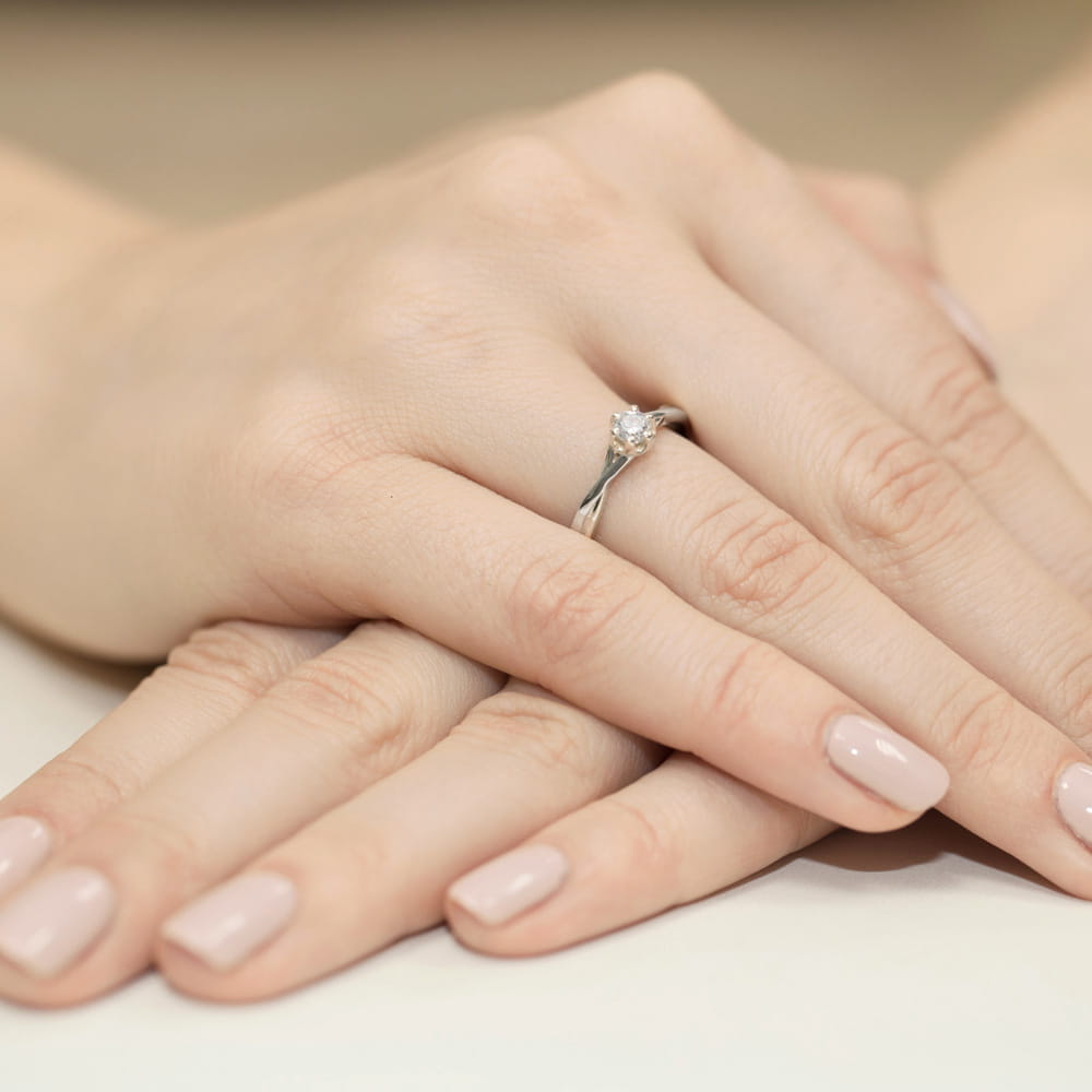 W0340.B3.LDW.05_4 Na dłoni z delikatnym manicure znajduje się srebrny pierścionek z diamentem.