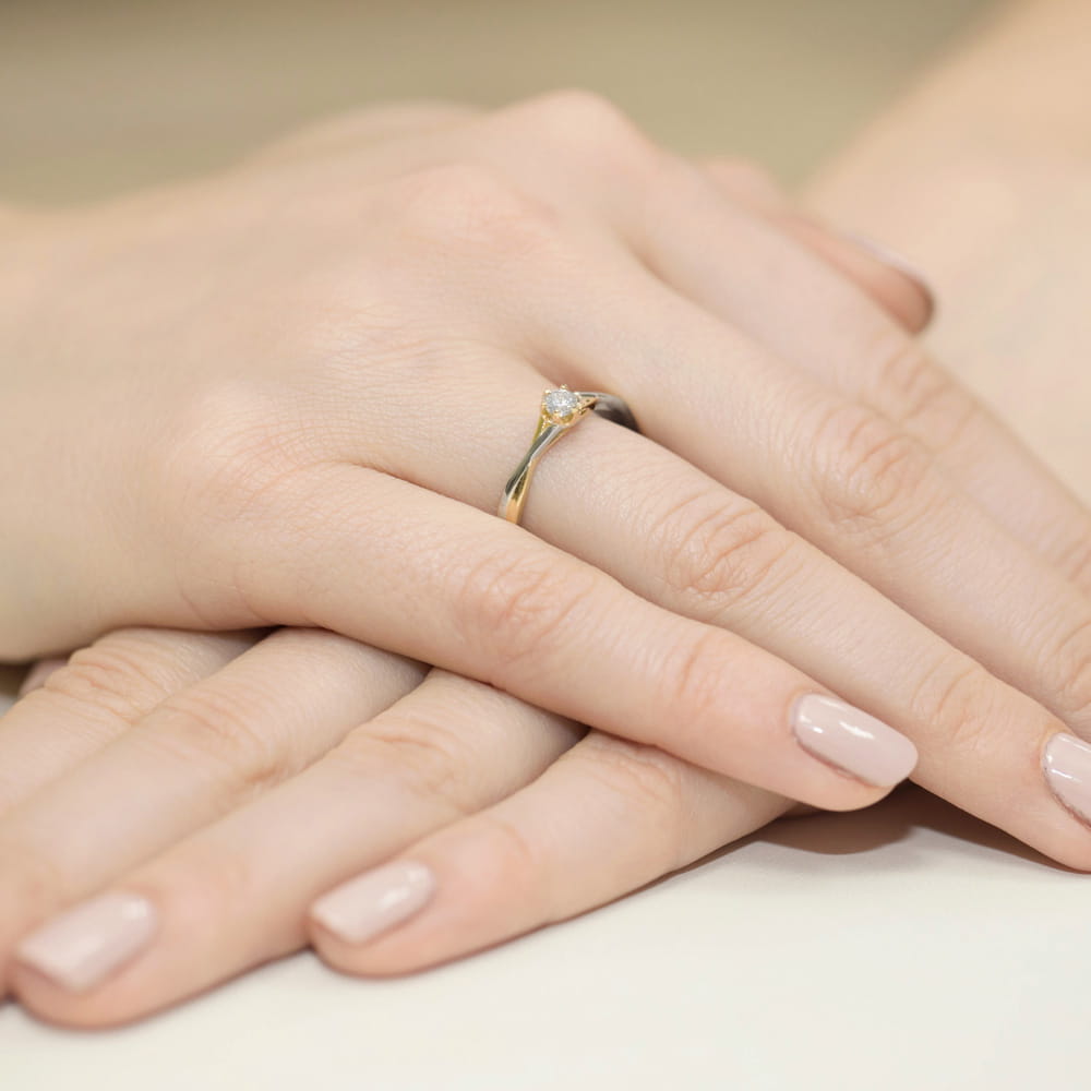 W0340.Z3.DIW.02_4 Złoty pierścionek z diamentem na palcu, dłonie z zadbanymi paznokciami w jasnym kolorze.
