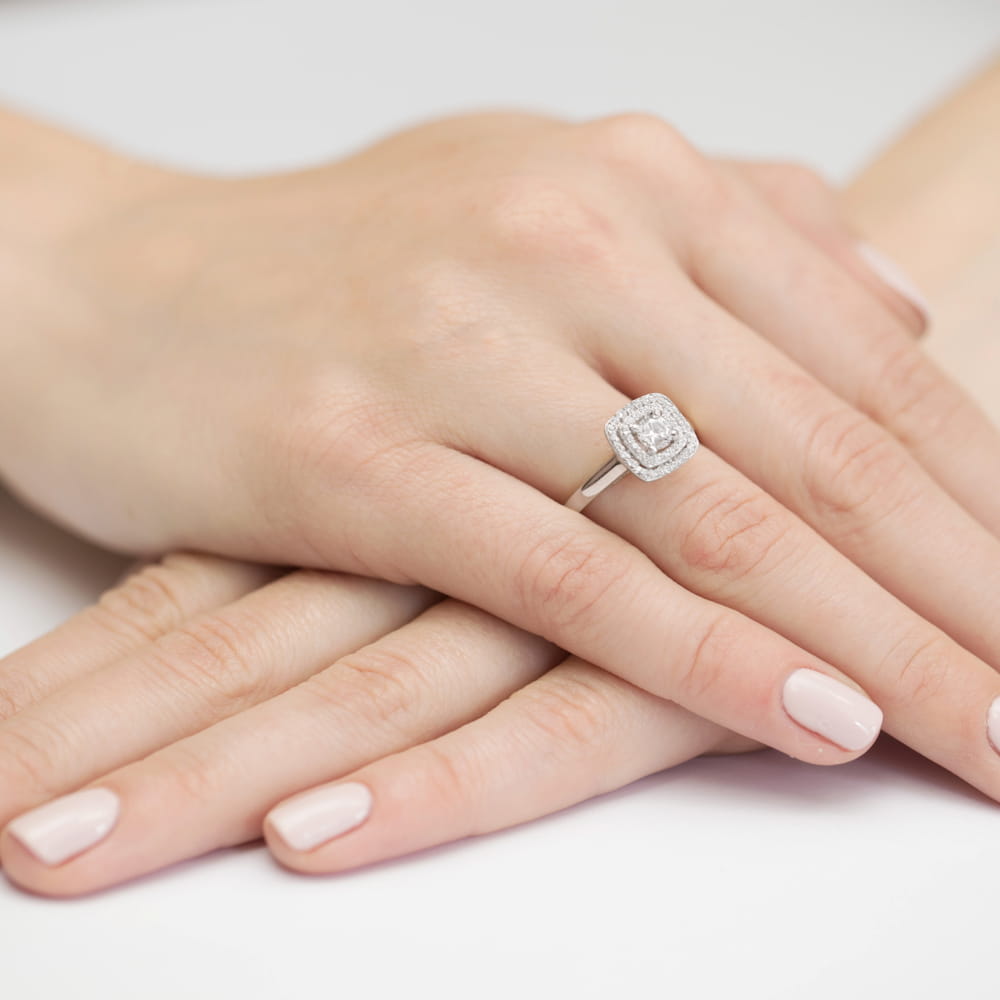 W0345.B3.DIW.01_4 Na dłoni z delikatnym manicure znajduje się srebrny pierścionek z diamentowym zdobieniem.