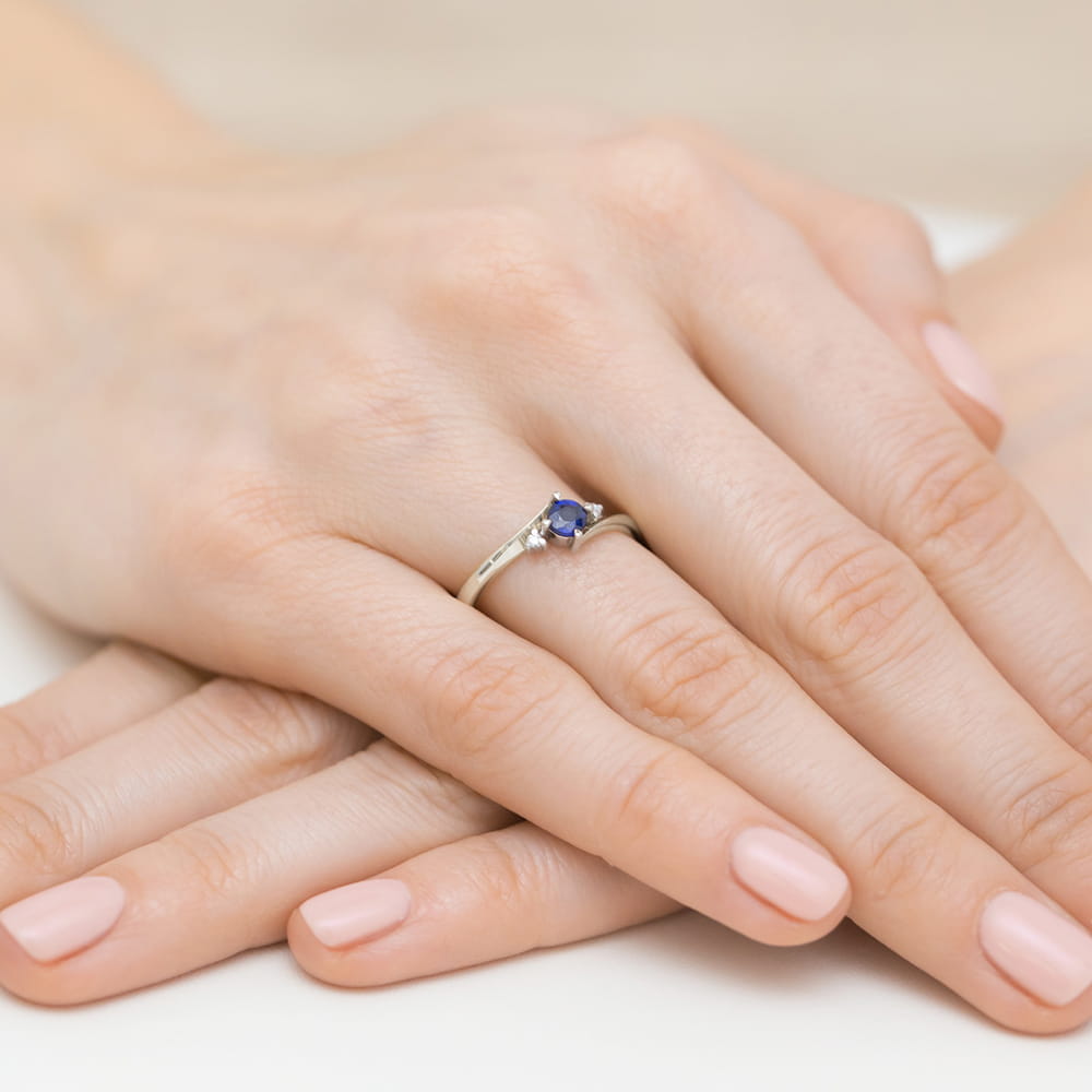 W0346.B3.SAB.02_6 Na dłoniach z delikatnym manicure znajduje się srebrny pierścionek z fioletowym kamieniem.