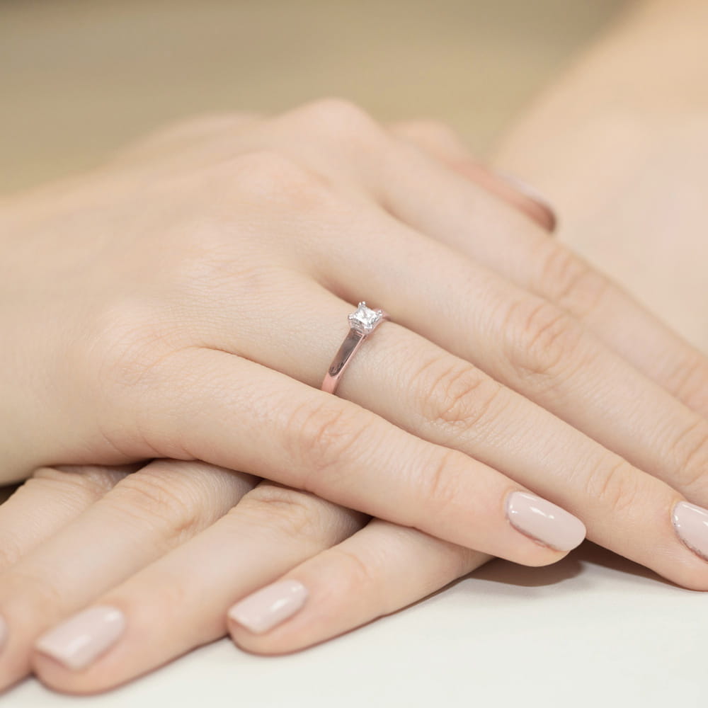 W0347.R3.DIW.01_4 Na dłoni z delikatnym manicure znajduje się srebrny pierścionek z diamentem.