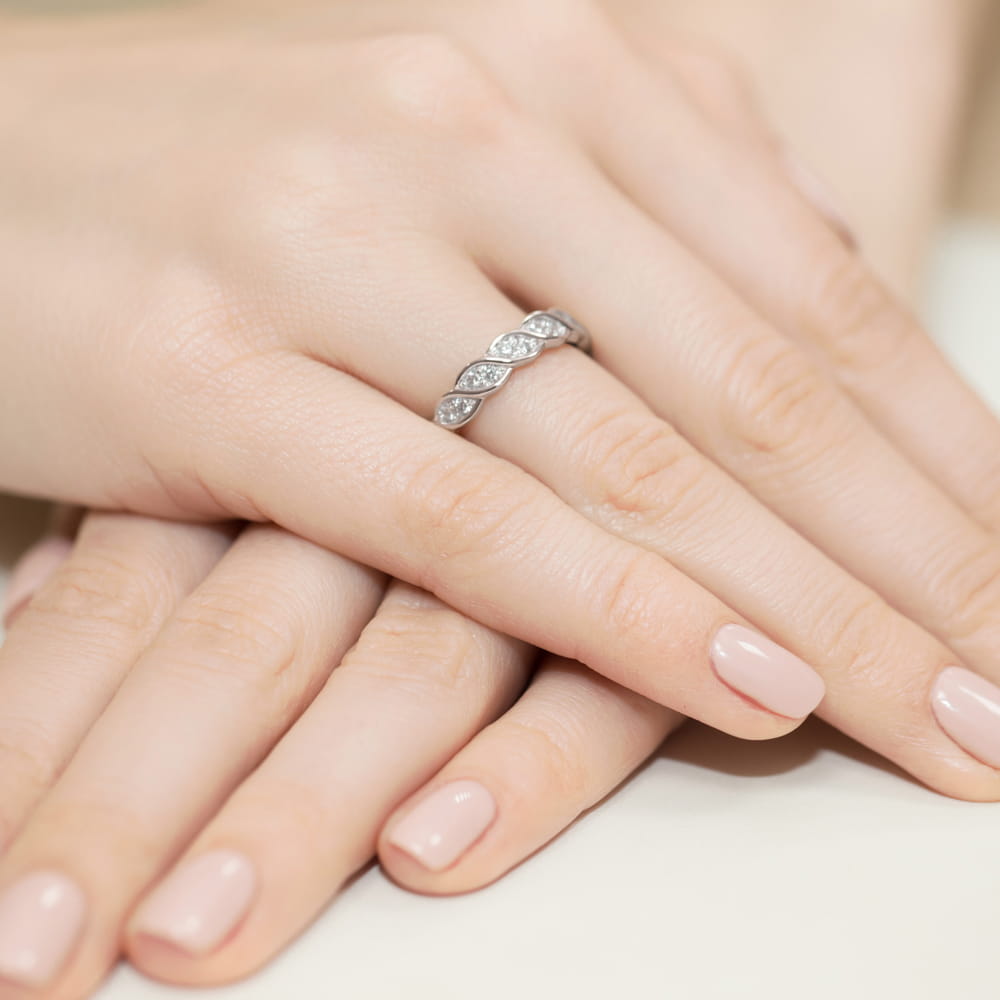 W0349.B3.DIW.01_4 Dwie ręce z delikatnym manicurem, na jednej z nich srebrny pierścionek z diamentami.