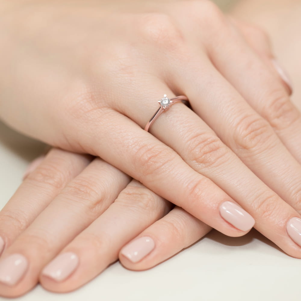 W0367.R3.DIW.01_4 Na dłoniach z delikatnym manicure znajduje się złoty pierścionek z diamentem.