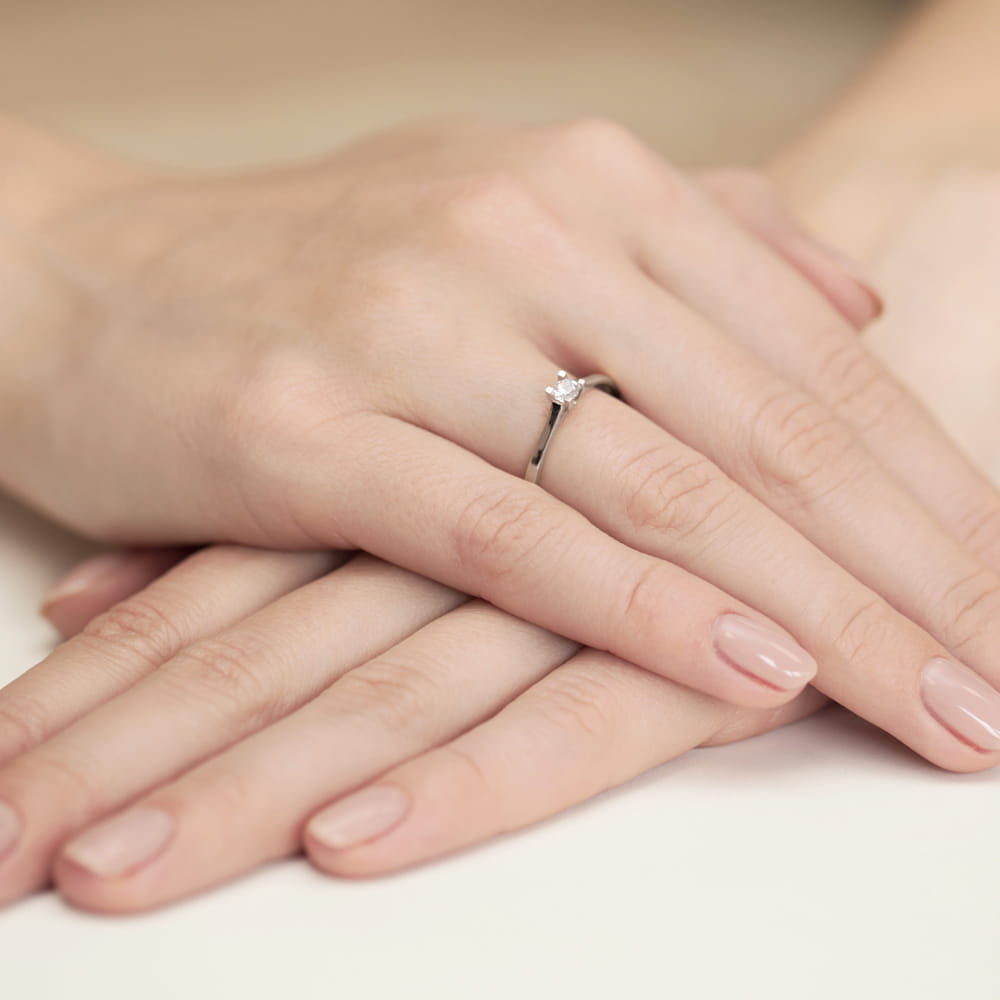 W0407.B3.DIW.01_4 Dwie dłonie z delikatnym pierścionkiem na jednym z palców, paznokcie w jasnym kolorze.