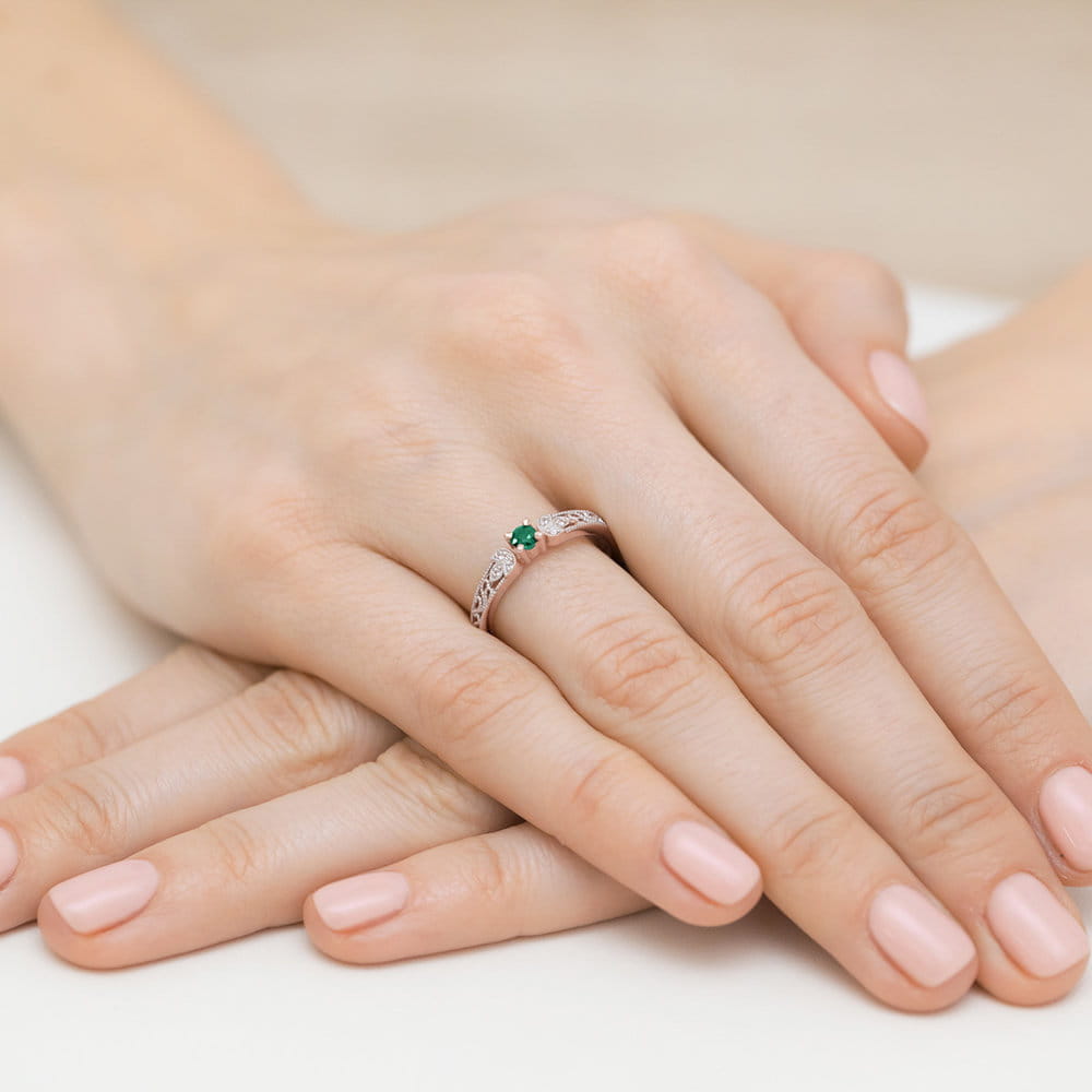 W0411.R3.EMG.01_4 Srebrny pierścionek z zielonym kamieniem na palcu, dłonie z delikatnym manicure w jasnym kolorze.