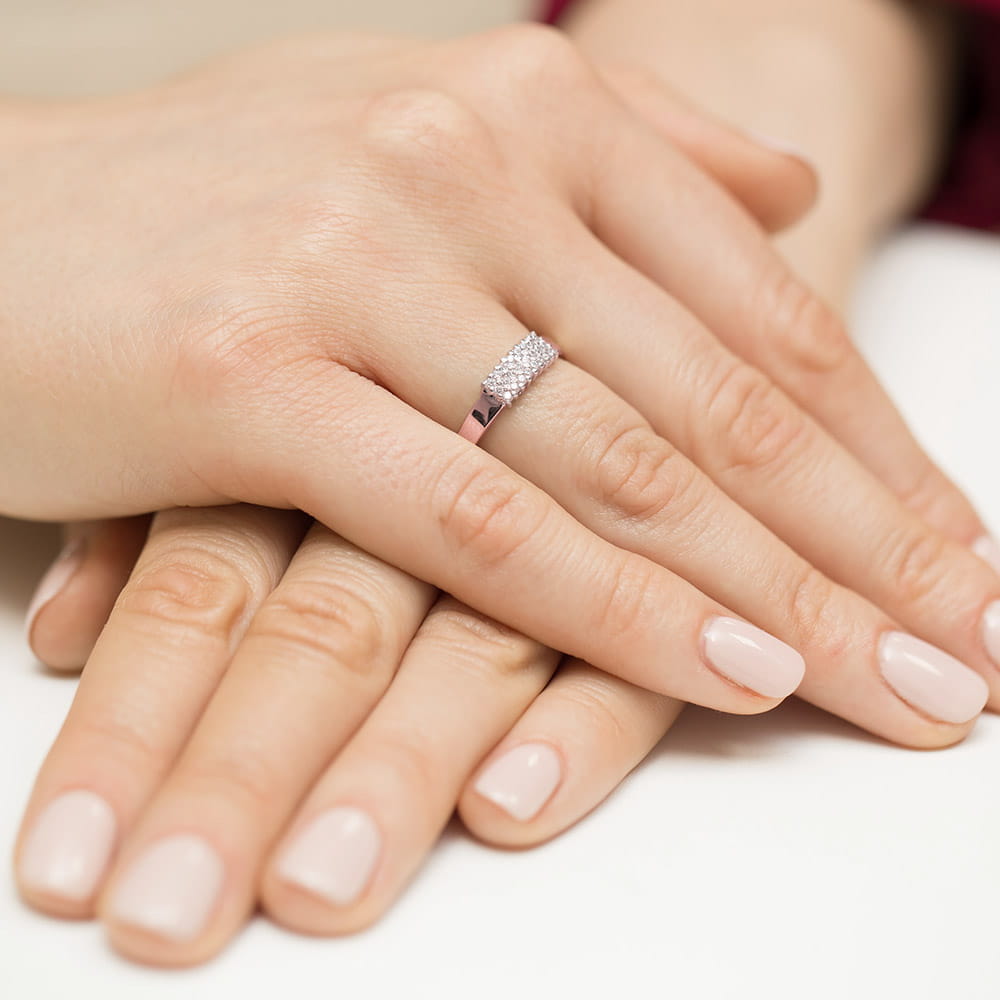 W0418.R3.DIW.01_4 Dwie dłonie z delikatnym manicurem, jedna z pierścionkiem z diamentami na palcu.