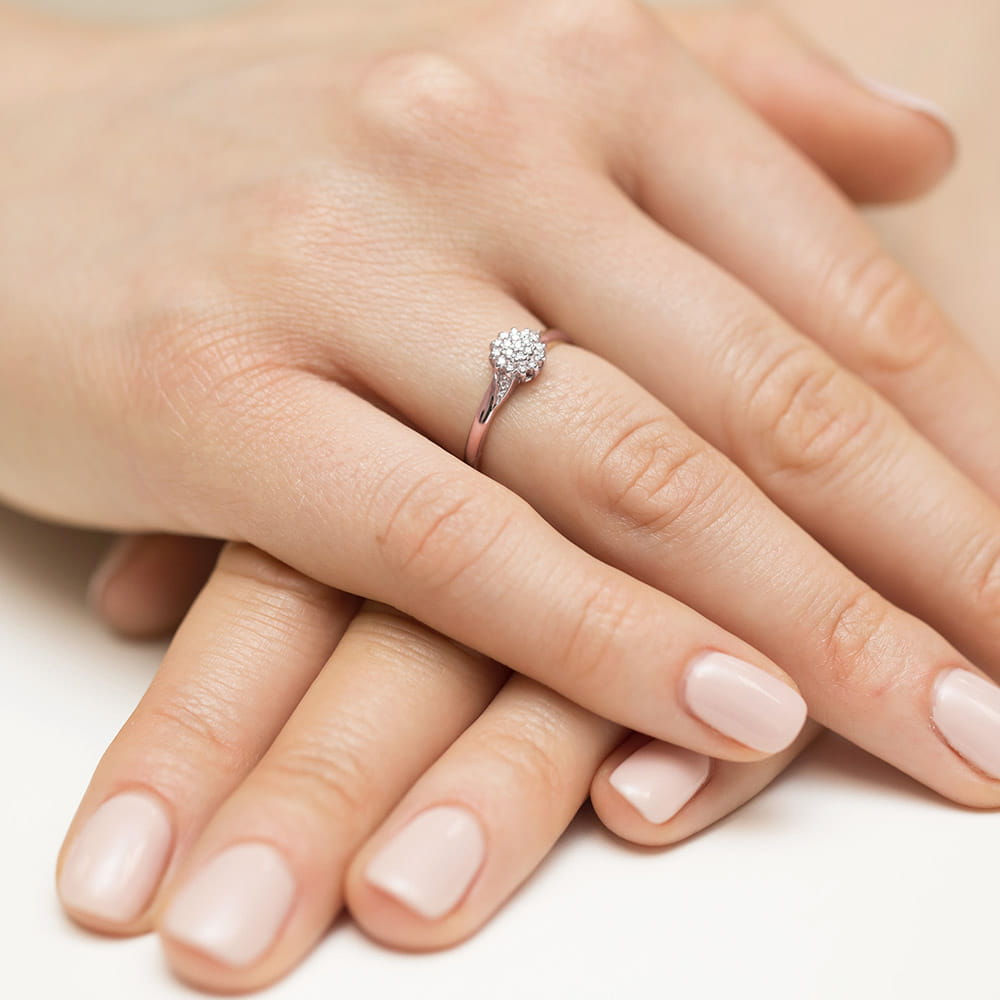 W0419.R3.DIW.01_4 Na dłoni z delikatnym manicure znajduje się pierścionek z małymi diamentami.