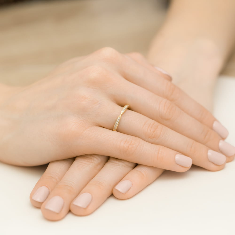 W0425.Z3.DIW.01_4 Złoty pierścionek na palcu jednej ręki, spoczywającej na drugiej dłoni z delikatnym manicure.
