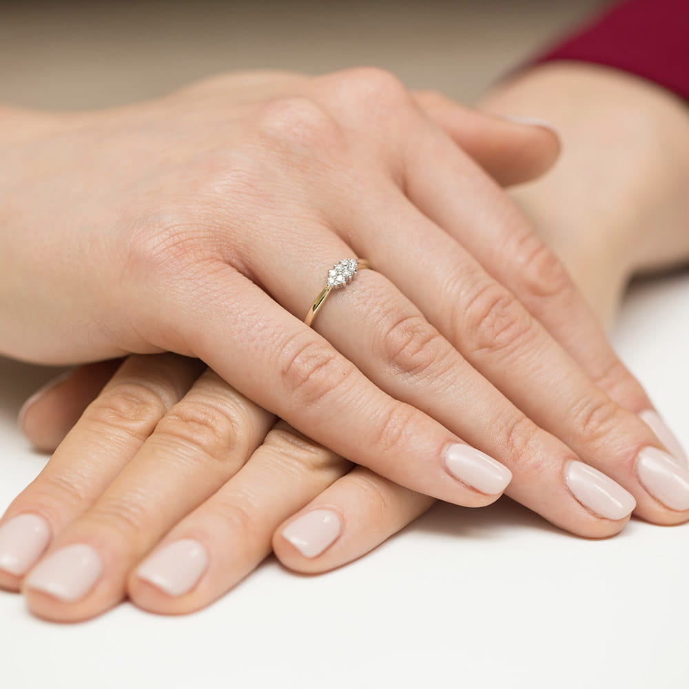 W0427.Z3.DIW.01_4 Dwie dłonie z delikatnym manicure, jedna z pierścionkiem z diamentami na palcu.