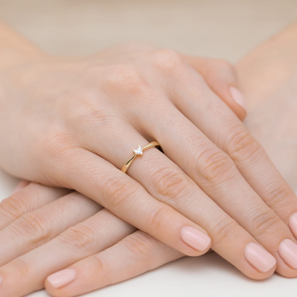 W0433.Z3.DIW.01_4 Złoty pierścionek z małym diamentem na palcu, dłonie z delikatnym manicure w jasnym kolorze.