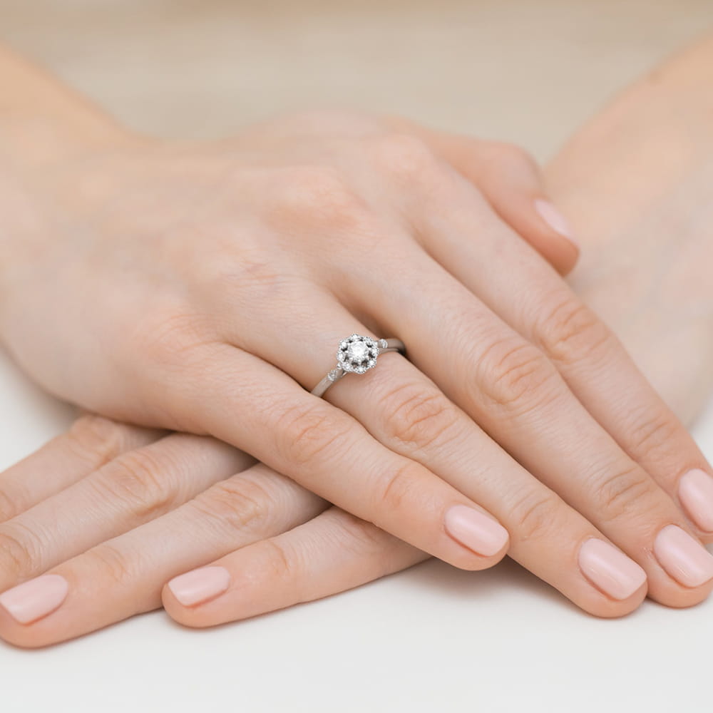 W0434.B3.DIW.01_4 Dwie dłonie z delikatnym manicure, jedna z pierścionkiem z dużym, błyszczącym kamieniem.