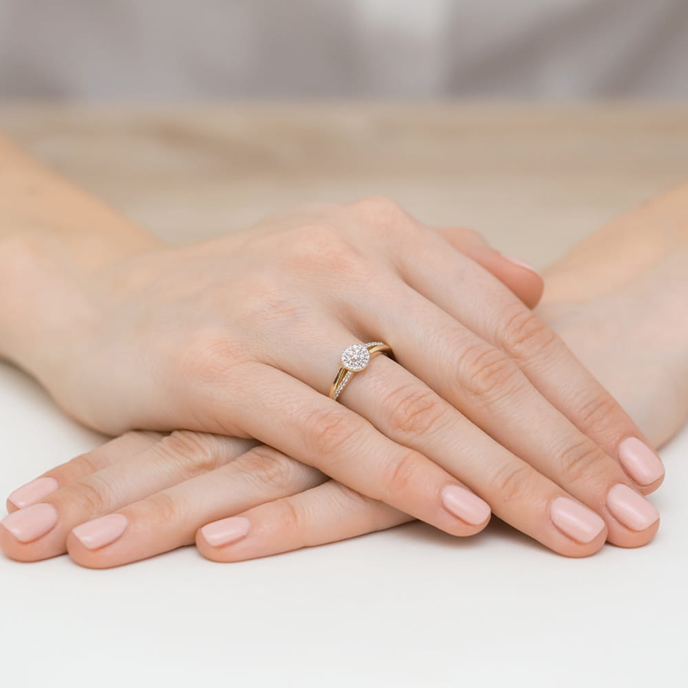 W0437.Z3.DIW.01_4 Złoty pierścionek z diamentem na palcu, dłonie z delikatnym manicure w odcieniu nude.