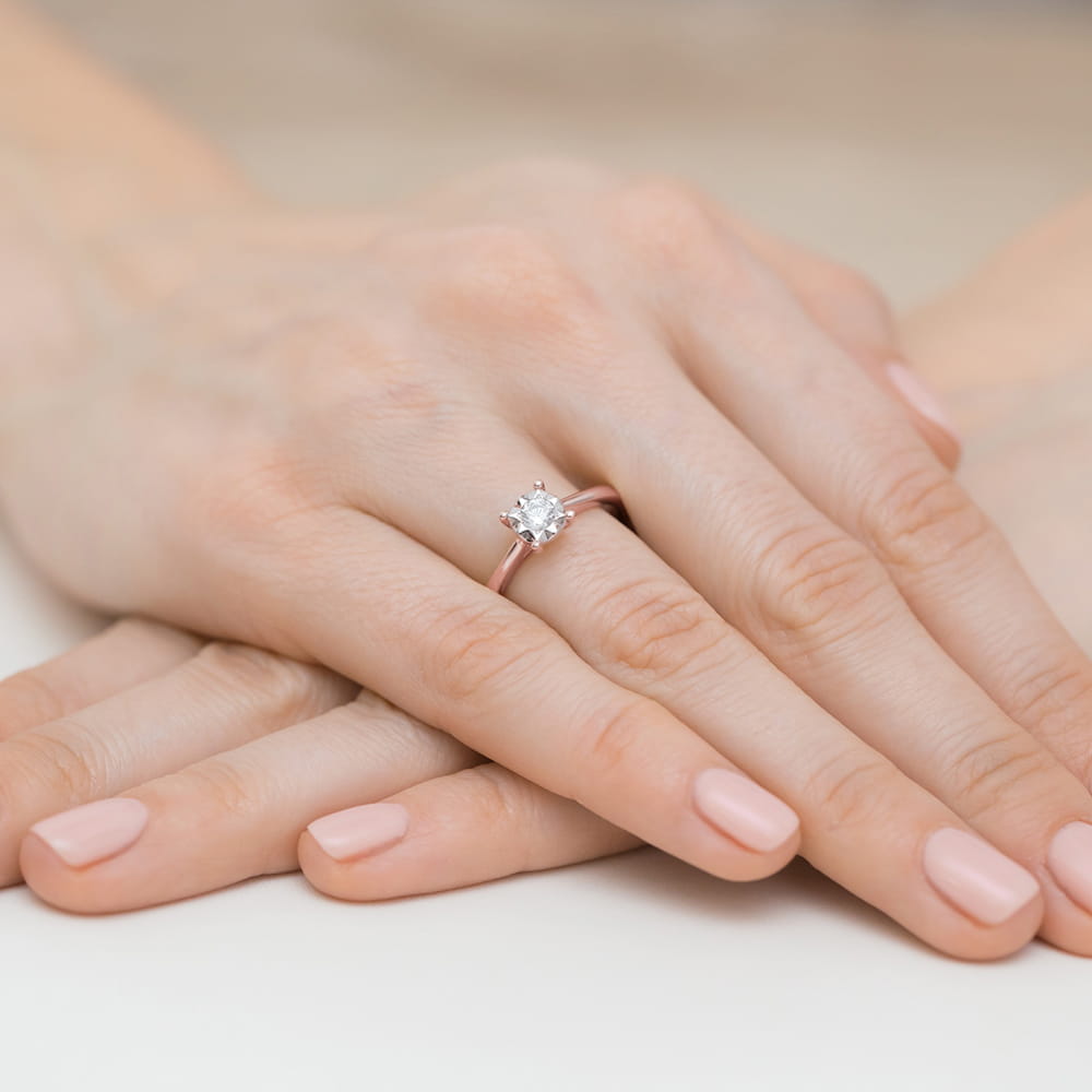 W0447.R3.DIW.01_4 Na dłoniach z delikatnym manicure znajduje się pierścionek z dużym, błyszczącym diamentem.