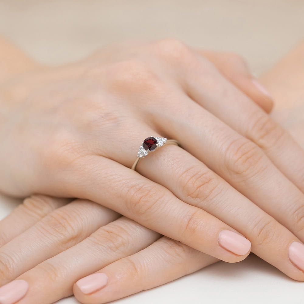 W0451.B3.GAR.01_4 Na dłoni z delikatnym manicure znajduje się pierścionek z rubinem i diamentami.