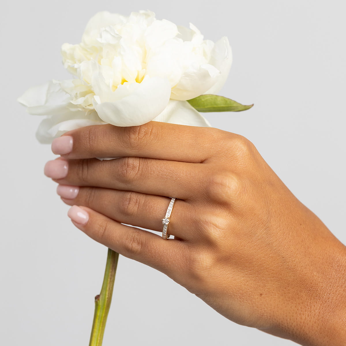 W0459.Z3.LDW.01_4 Ręka trzymająca białą piwonię, na palcu pierścionek z diamentami.