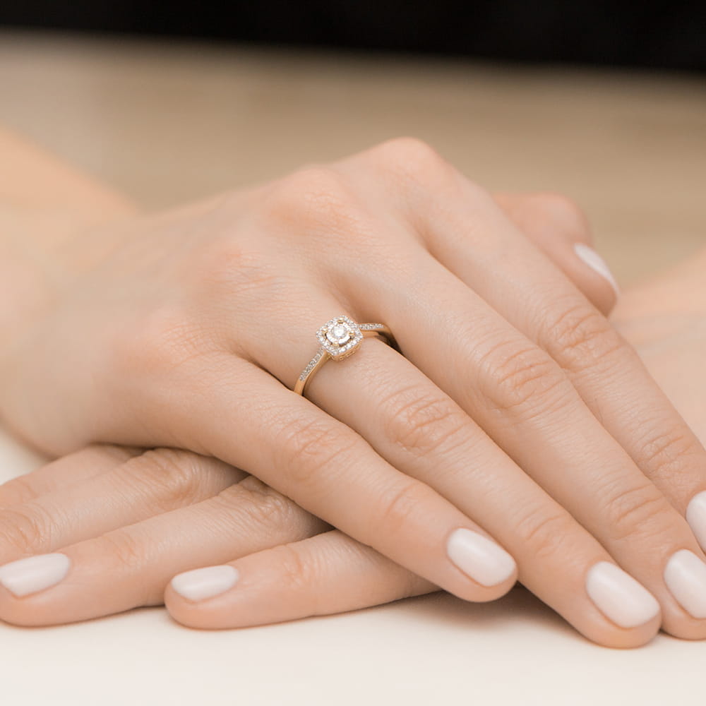 W0462.Z3.LDW.01_4 Złoty pierścionek z diamentem na palcu z zadbanymi, jasnymi paznokciami.