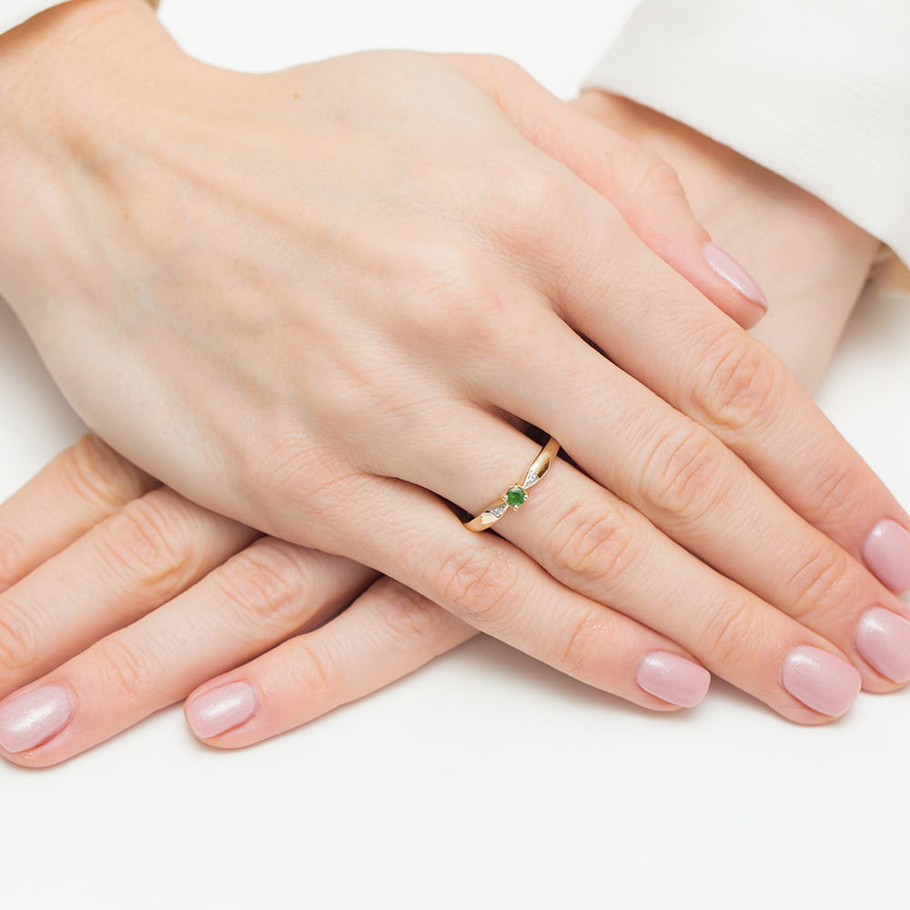 W0469.Z3.EMG.01_4 Dwie dłonie z delikatnym pierścionkiem z zielonym kamieniem na palcu, z różowym manicure.