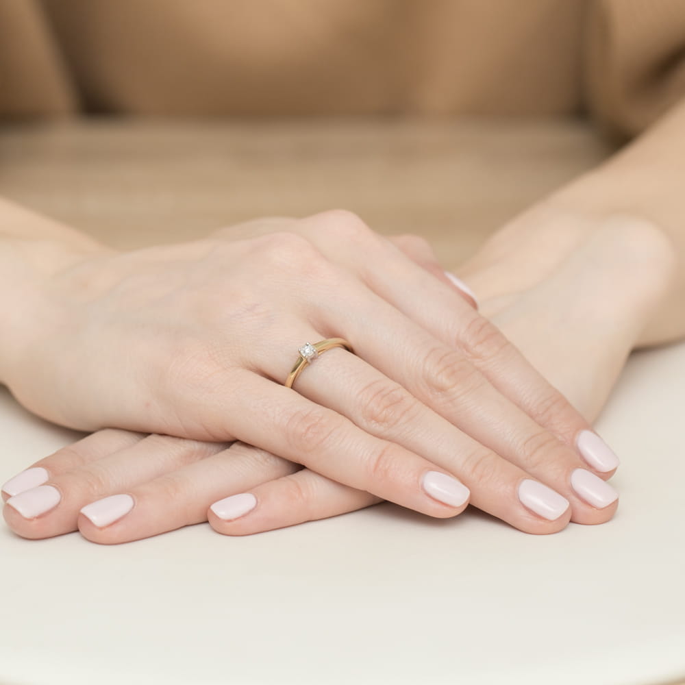 W0471.Z3.DIW.01_4 Dwie ręce z delikatnym pierścionkiem na palcu, z różowym manicure na paznokciach.