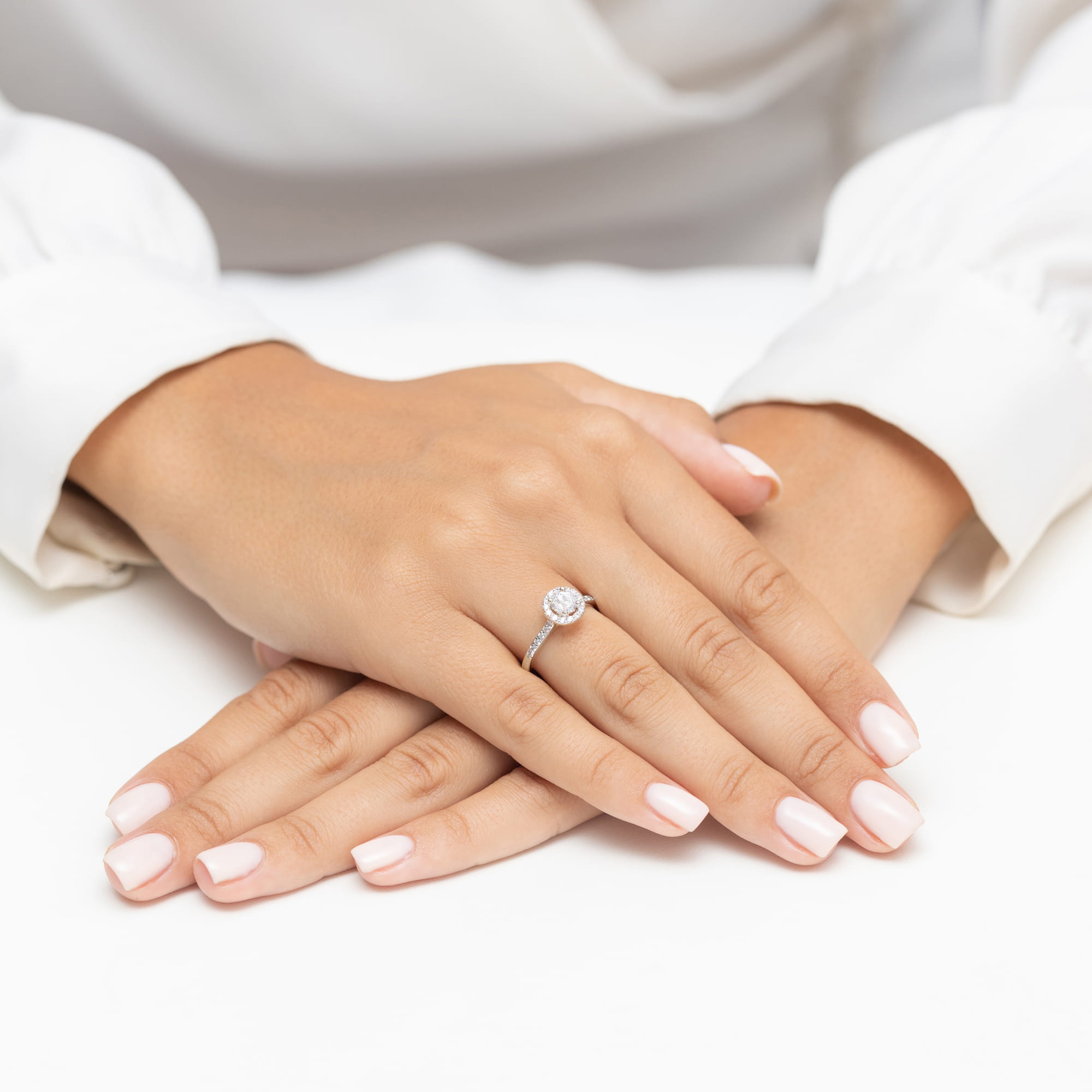 W0477.B3.LDW.01_4 Dłoń z pierścionkiem na palcu, z zadbanymi, jasnymi paznokciami, leży na białym tle.