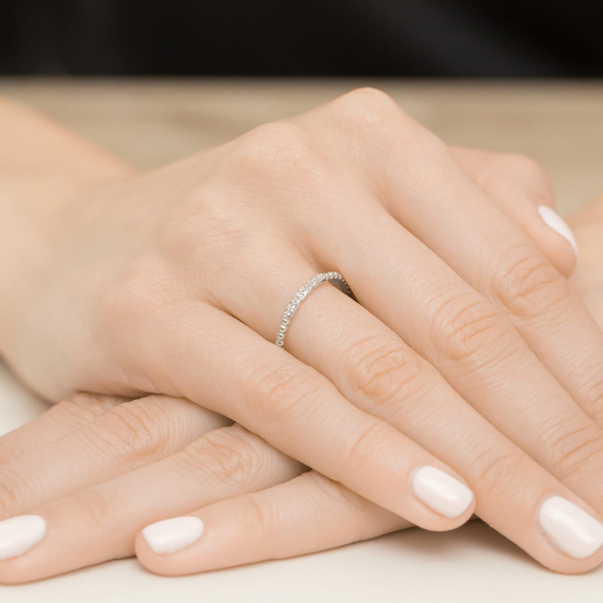 W0479.B3.DIW.01_4 Na dłoni widać delikatny pierścionek z małymi diamentami, otoczony zadbanymi, jasnymi paznokciami.