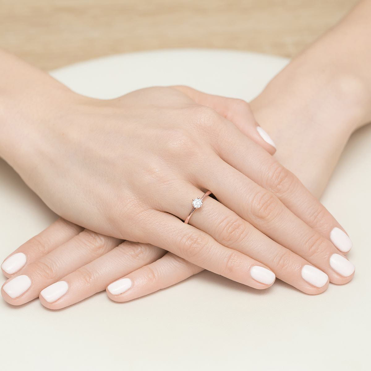W0496.R3.DIW.01_4 Dwie ręce z białym manicure, jedna z pierścionkiem z diamentem na palcu.