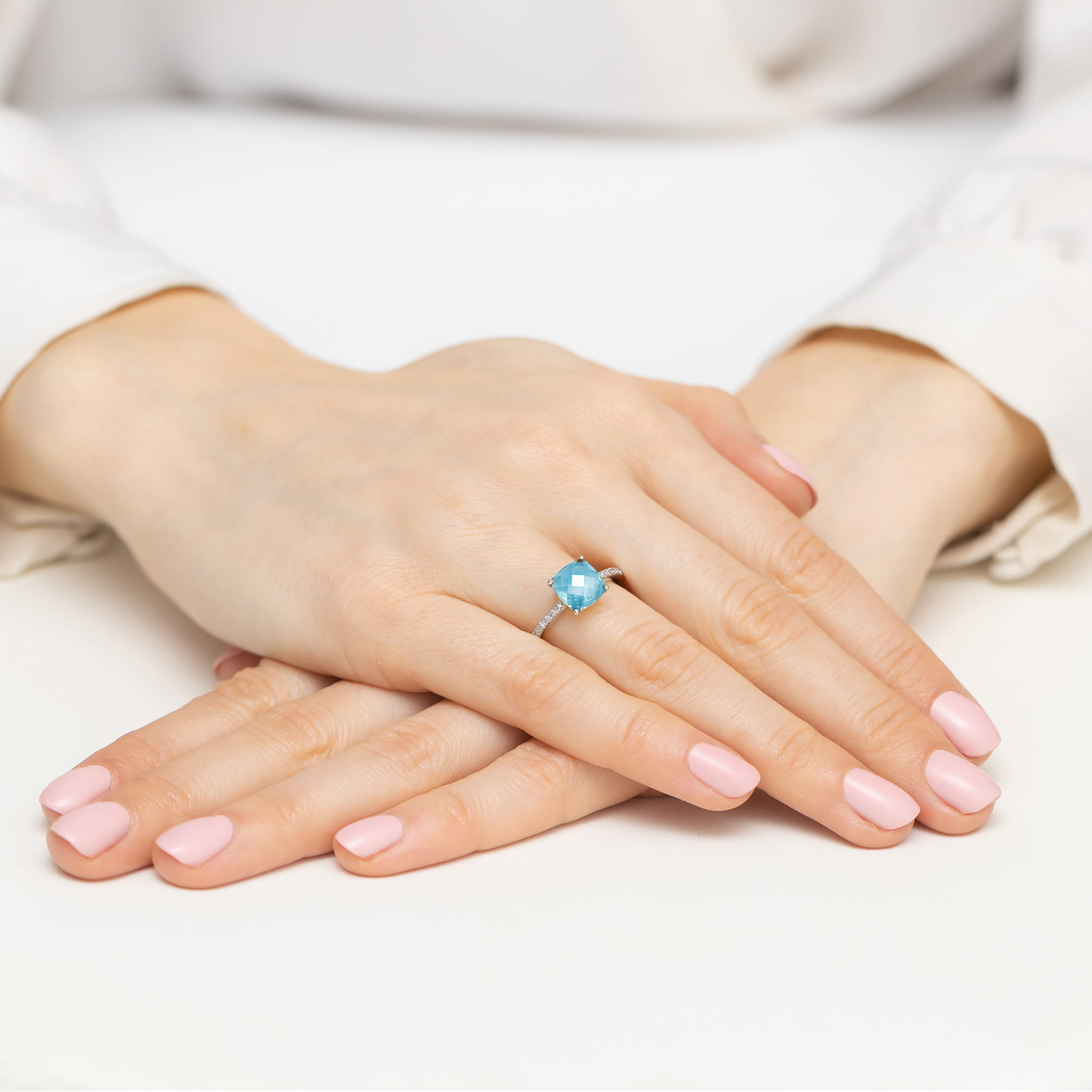 W0511.B3.TOB.01_4 Dwie ręce z różowym manicure, jedna z pierścionkiem z niebieskim kamieniem na palcu.