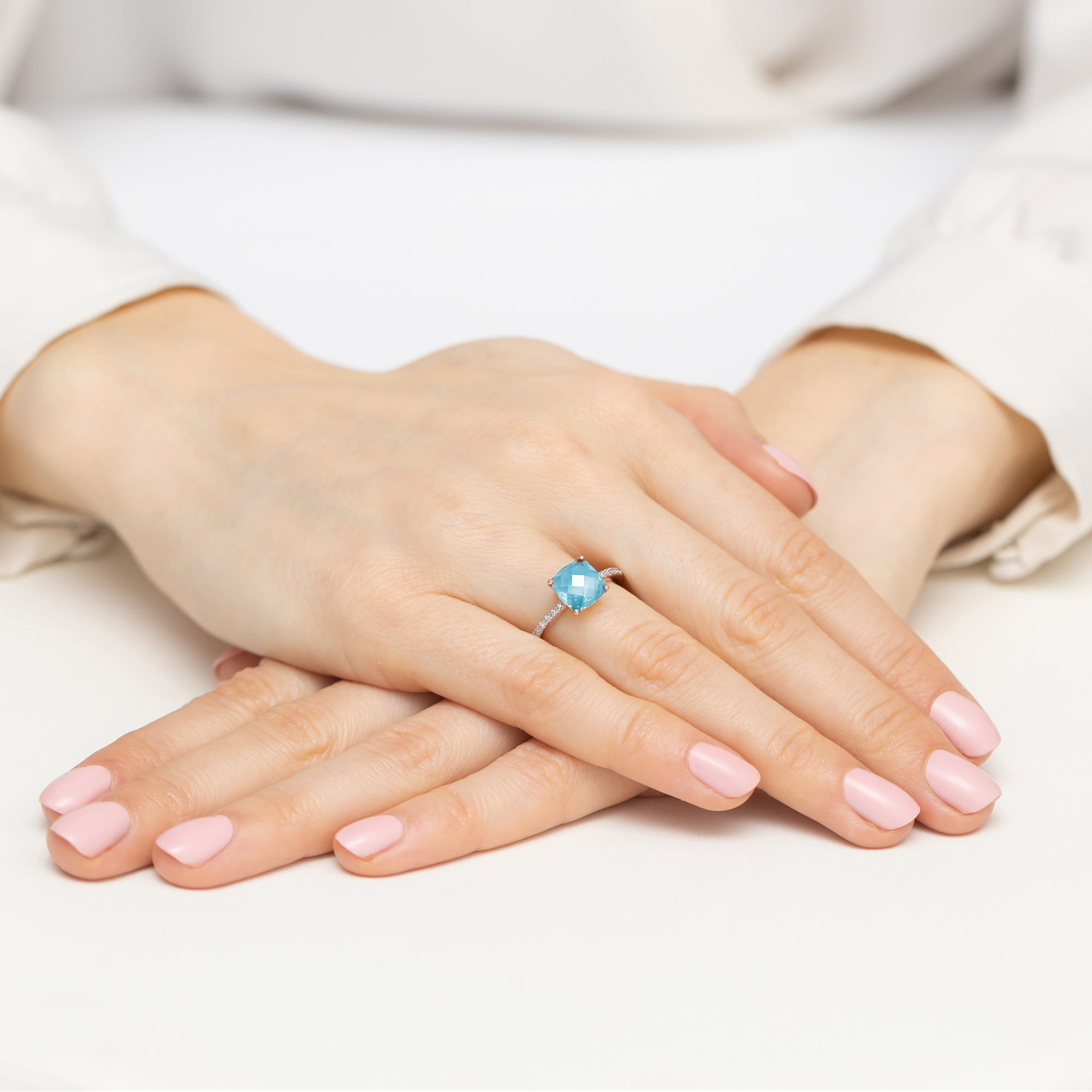 W0511.R3.TOB.01_4 Dwie ręce z różowym manicure, jedna z pierścionkiem z niebieskim kamieniem na palcu.