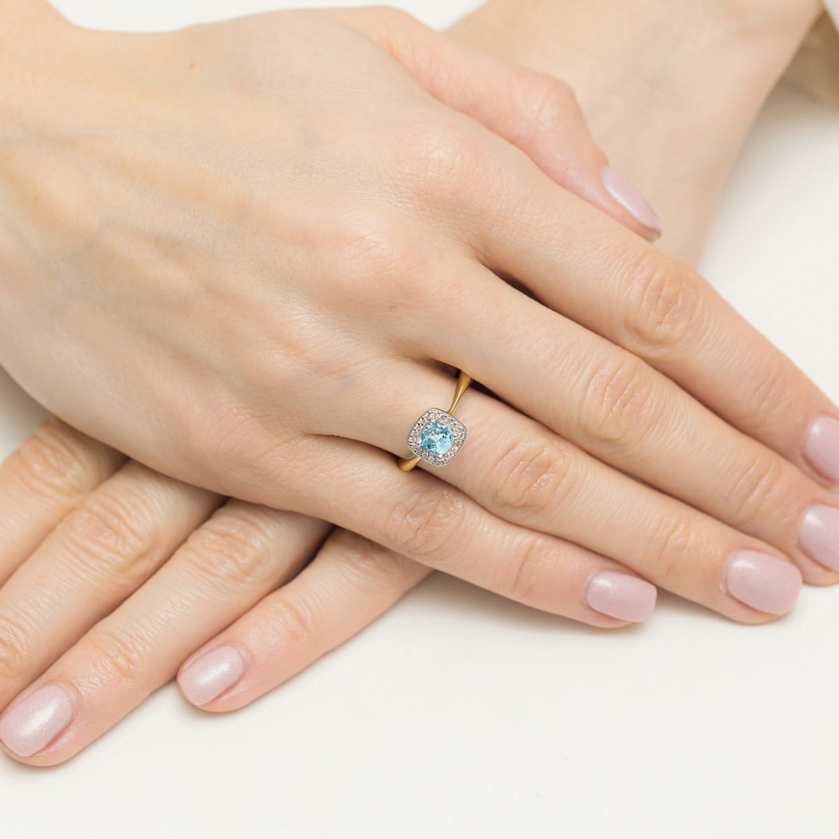 W0514.Z3.TOB.01_4 Złoty pierścionek z niebieskim kamieniem na palcu, dłonie z delikatnym manicure.