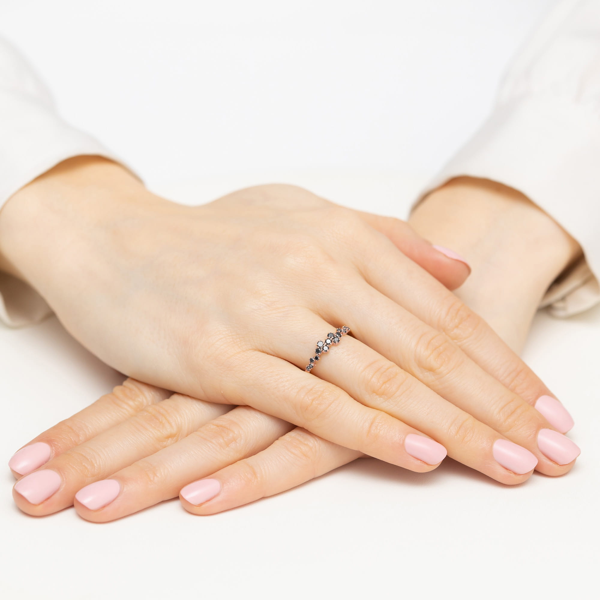 W0528.R3.DIB.01_4 Dwie ręce z różowym manicure, jedna na drugiej, z delikatnym pierścionkiem na palcu.