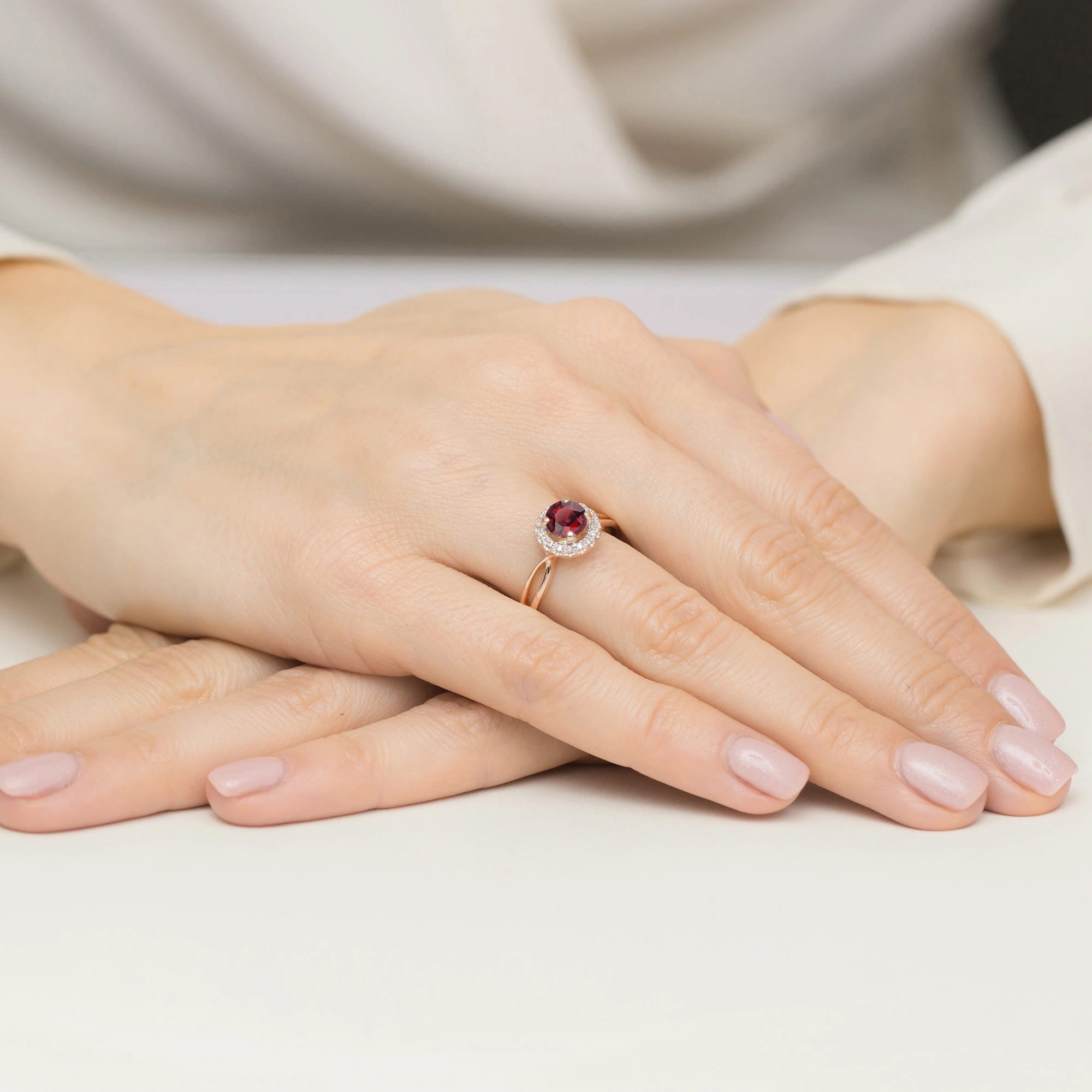 W0538.R3.RUR.01_4 Na dłoni widoczny pierścionek z czerwonym kamieniem otoczonym diamentami, dłonie z zadbanymi paznokciami.