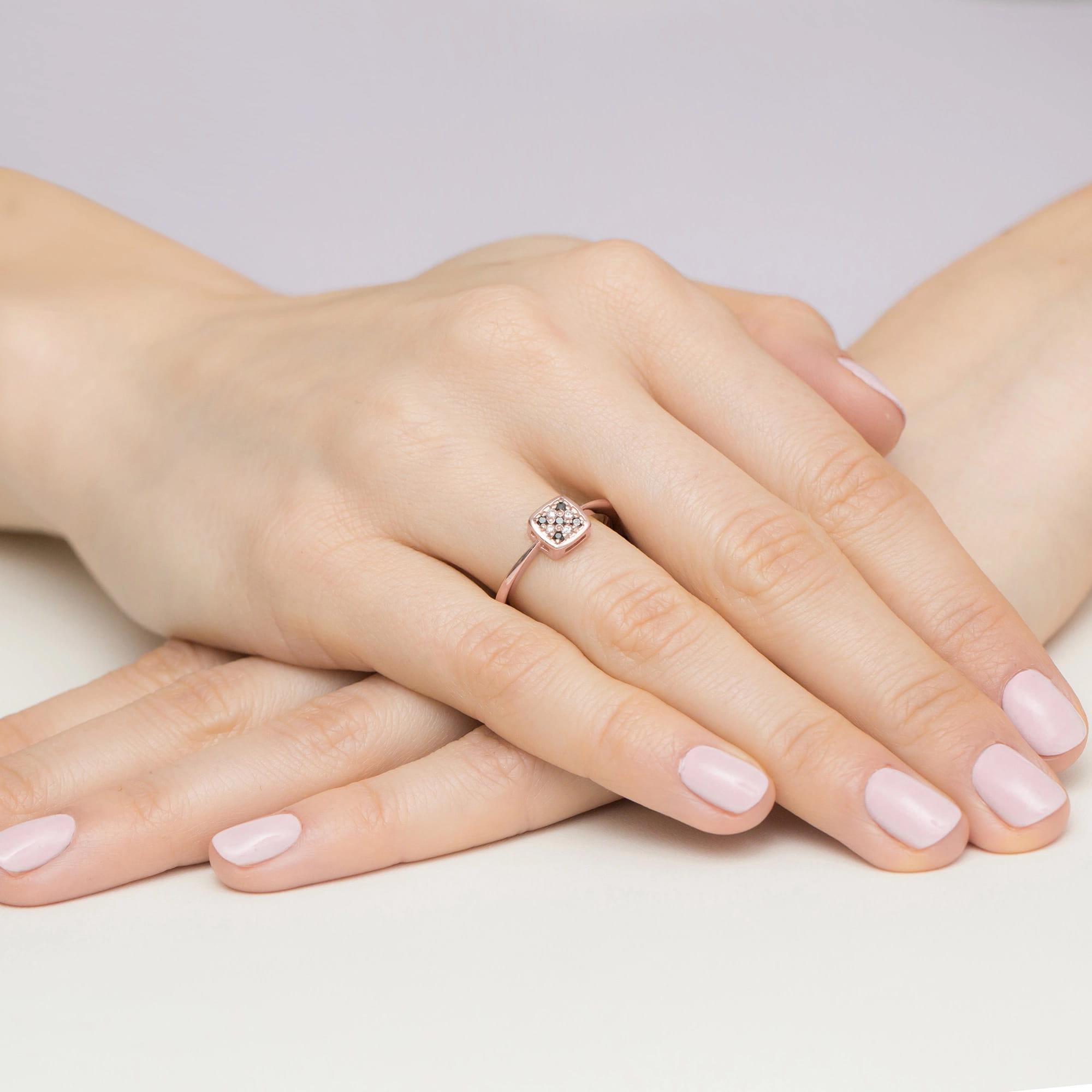 W0555.R3.DIB.01_4 Różowe złote pierścionek z małym diamentem na palcu, dłonie z zadbanymi paznokciami w jasnym kolorze.