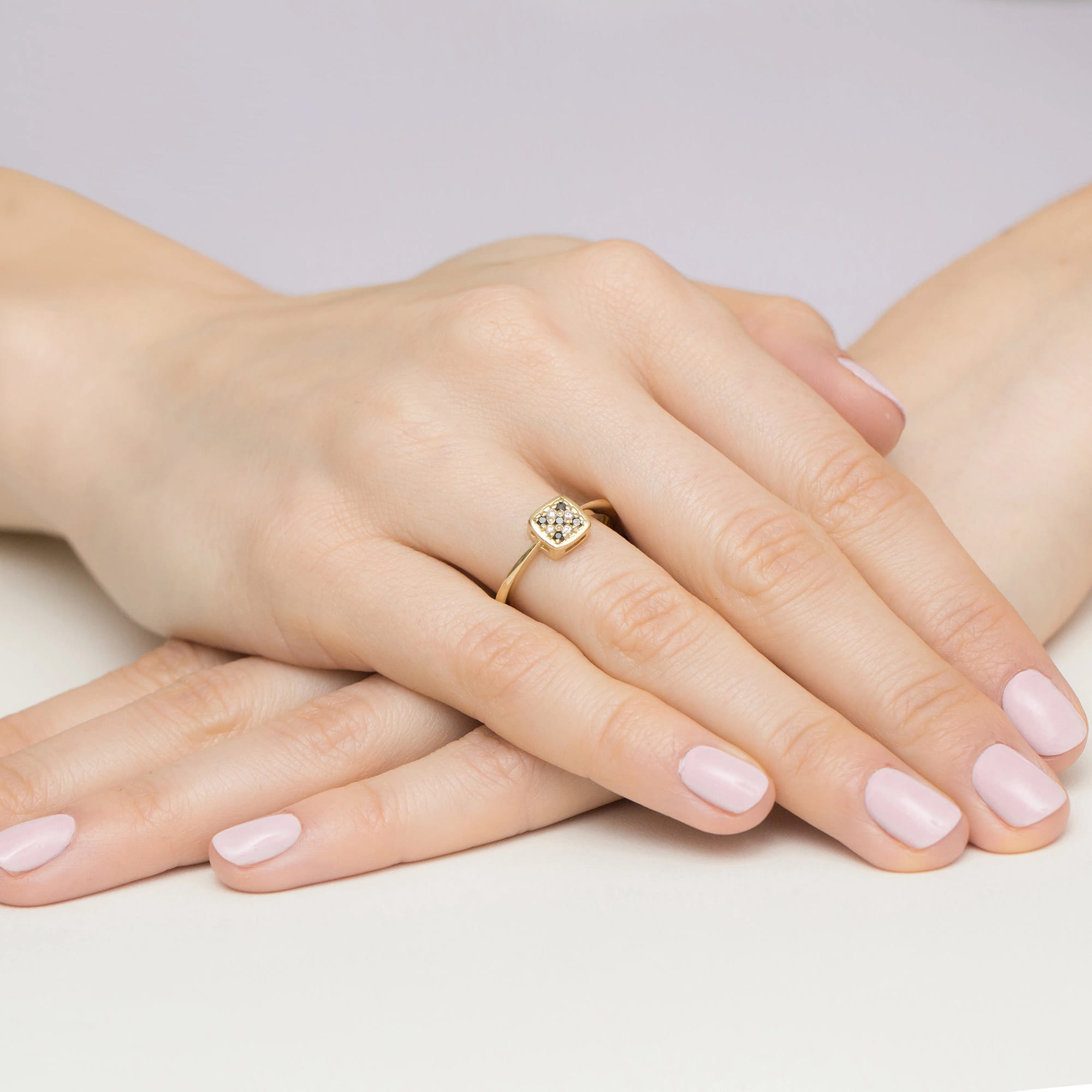 W0555.Z3.DIB.01_4 Złoty pierścionek z ozdobnym kamieniem na palcu, dłonie z delikatnym manicure w jasnym kolorze.