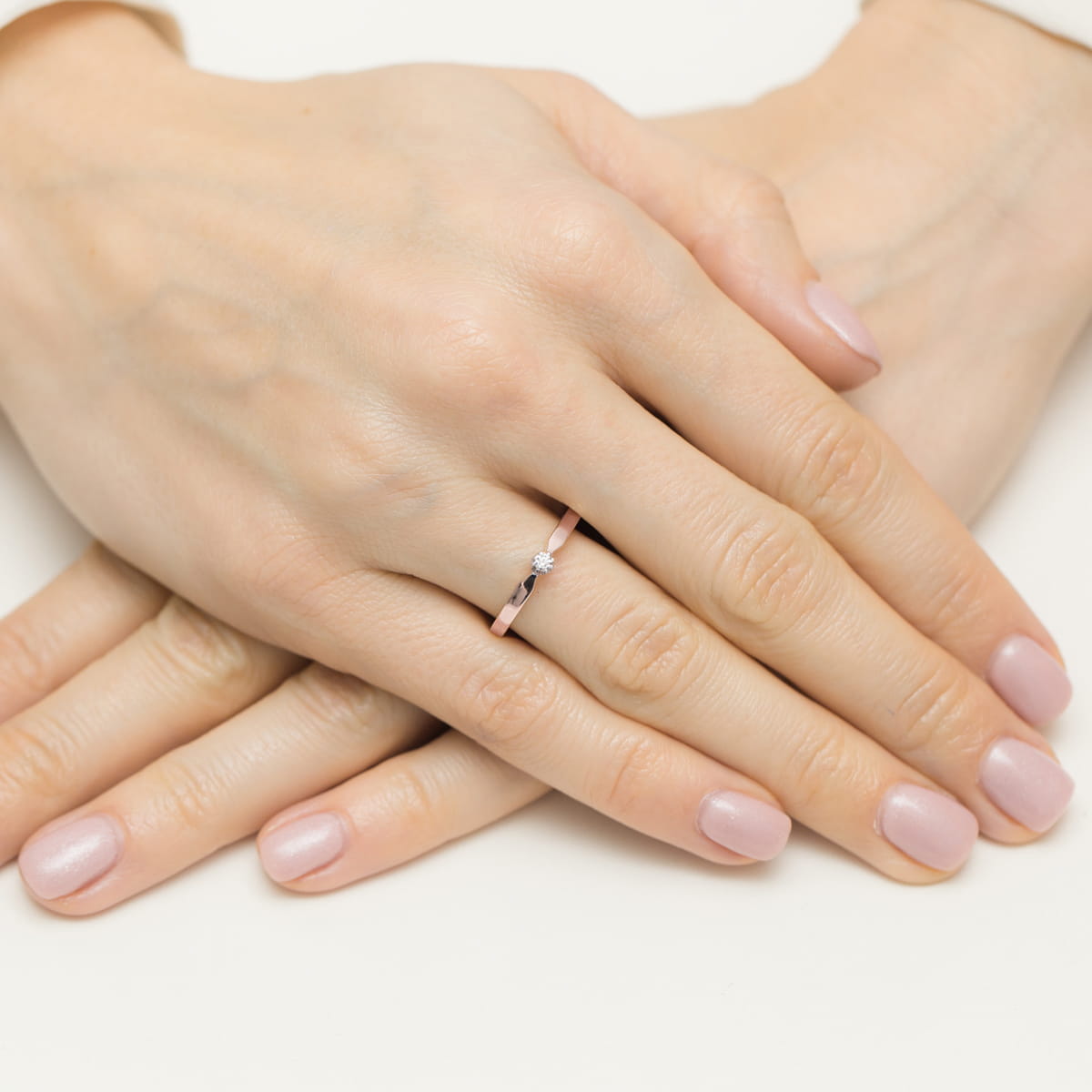 W0561.R3.DIW.01_4 Dwie ręce z delikatnym pierścionkiem na palcu, paznokcie w jasnym kolorze.