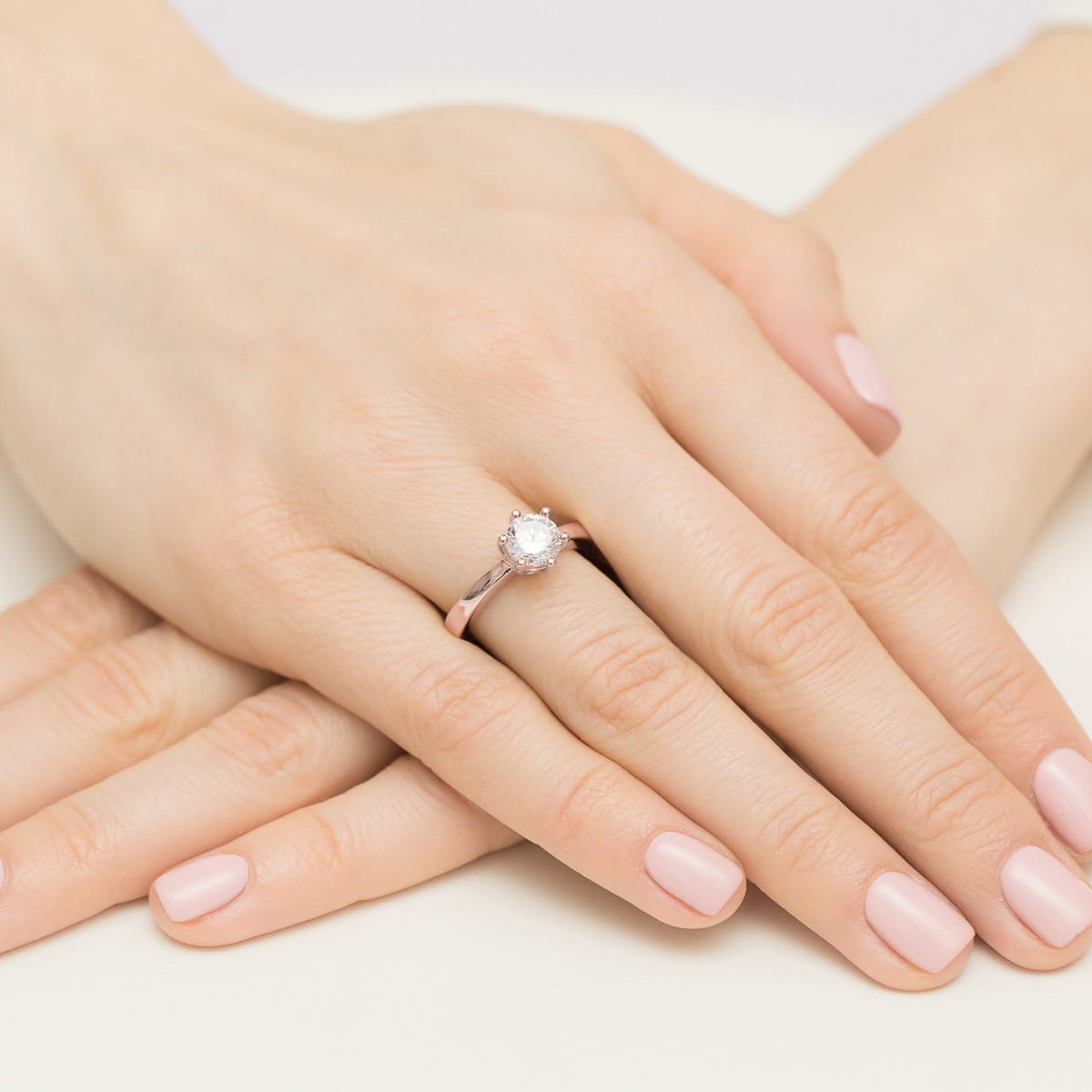 W0563.R3.LDW.04_4 Dwie ręce z delikatnym manicure, na jednym z palców pierścionek z dużym, okrągłym diamentem.