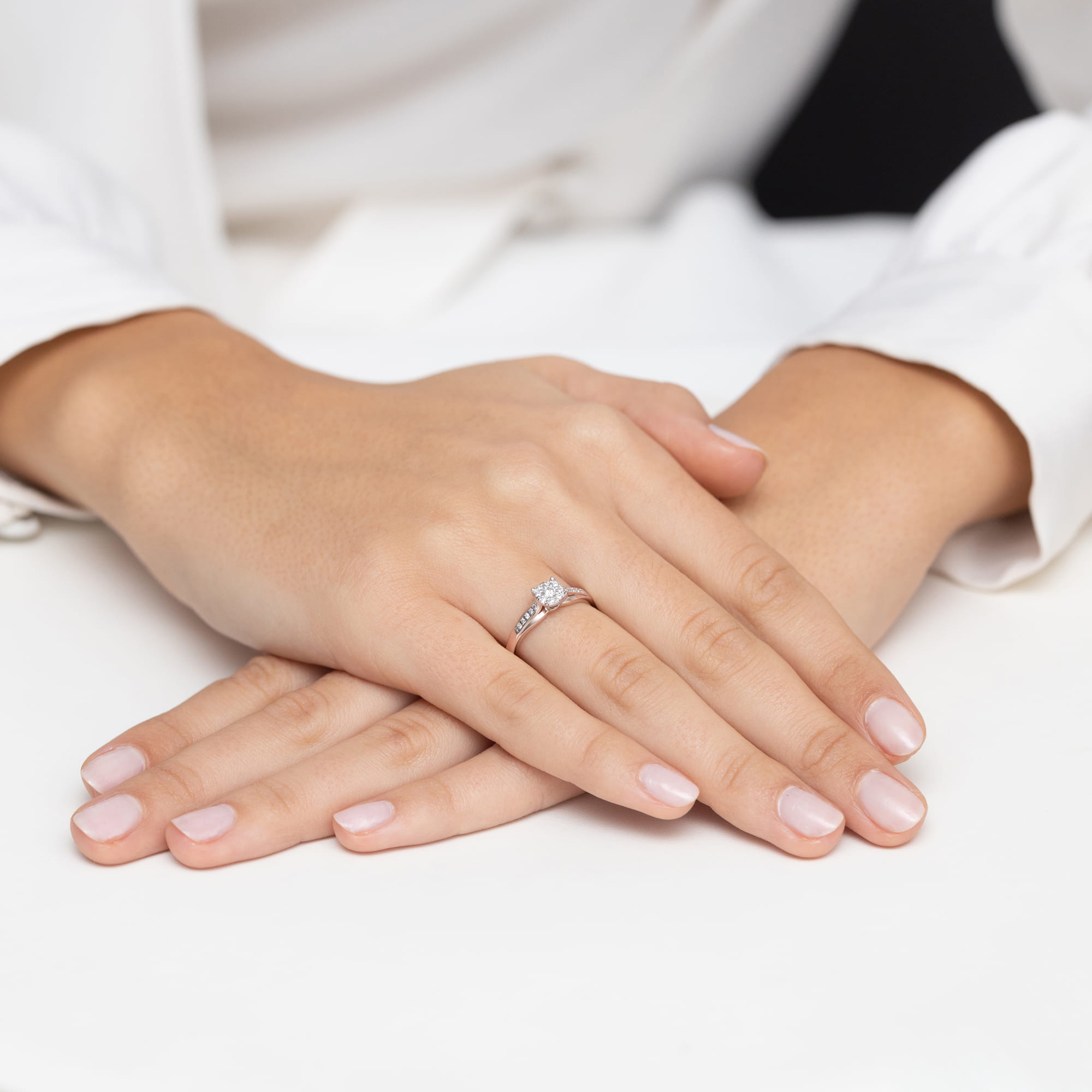 W0564.R3.DIW.01_4 Na dłoniach z delikatnym manicure znajduje się srebrny pierścionek z diamentem.