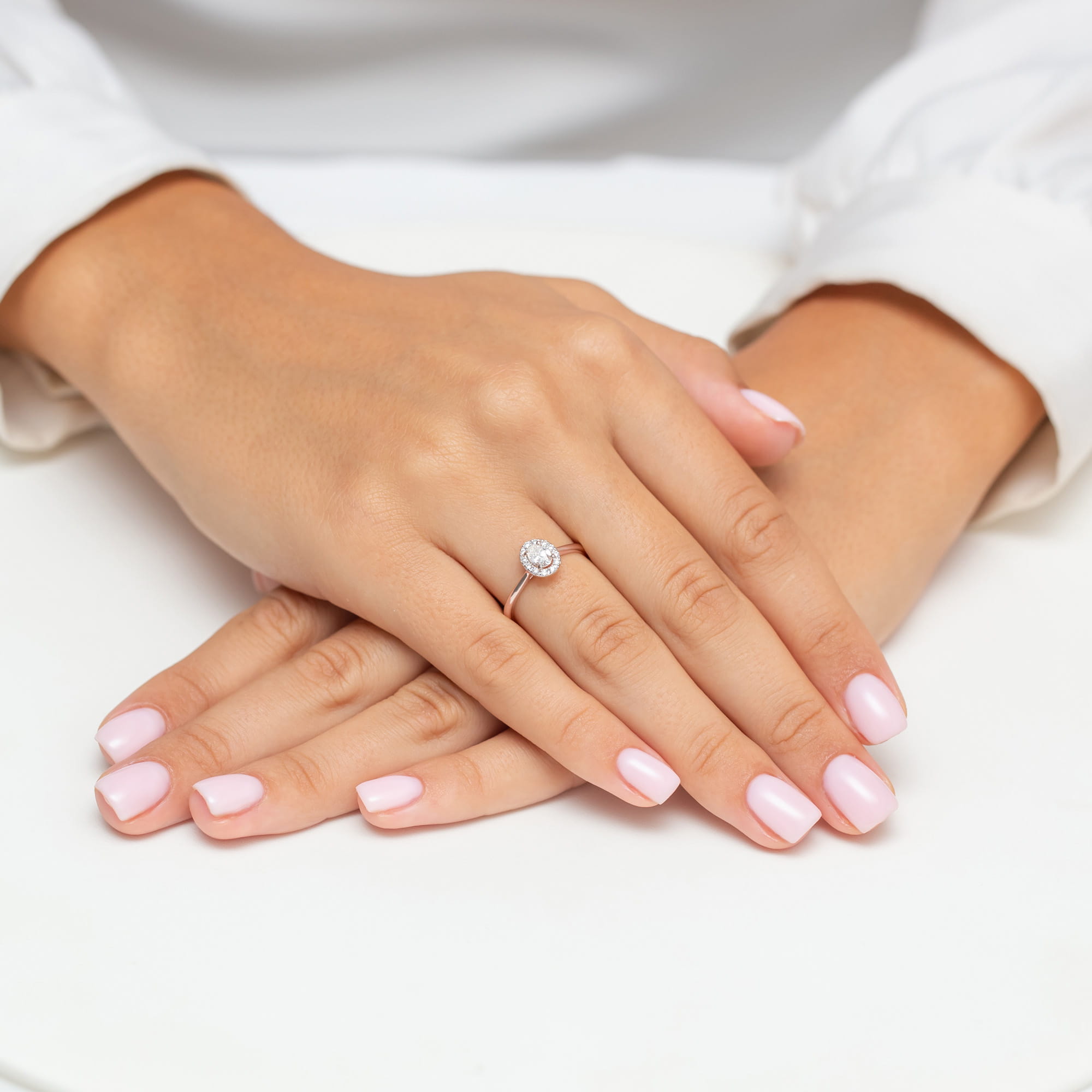 W0583.R3.DIW.01_4 Dłonie z różowymi paznokciami, na jednej z nich pierścionek z dużym, okrągłym diamentem.