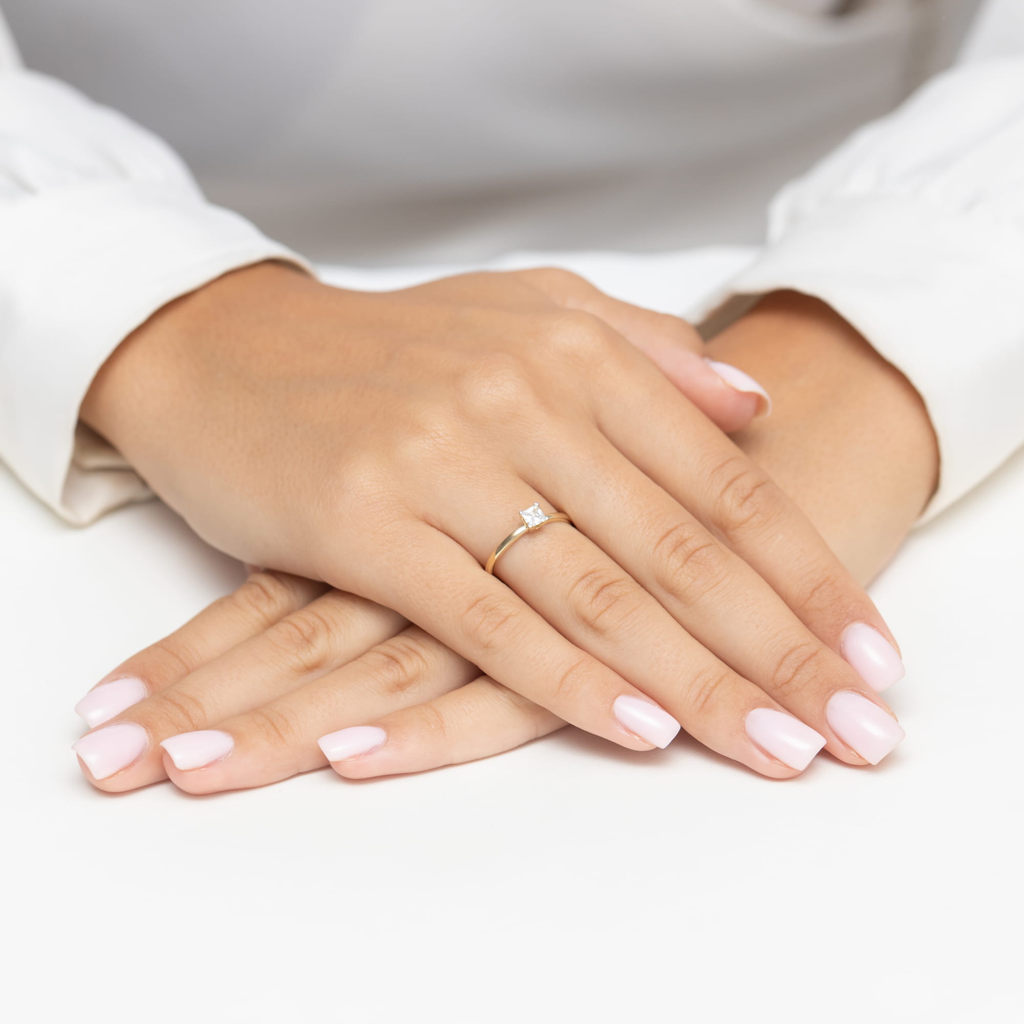 W0587.Z3.DIW.01_4 Na dłoniach z różowym manicure znajduje się złoty pierścionek z diamentem.