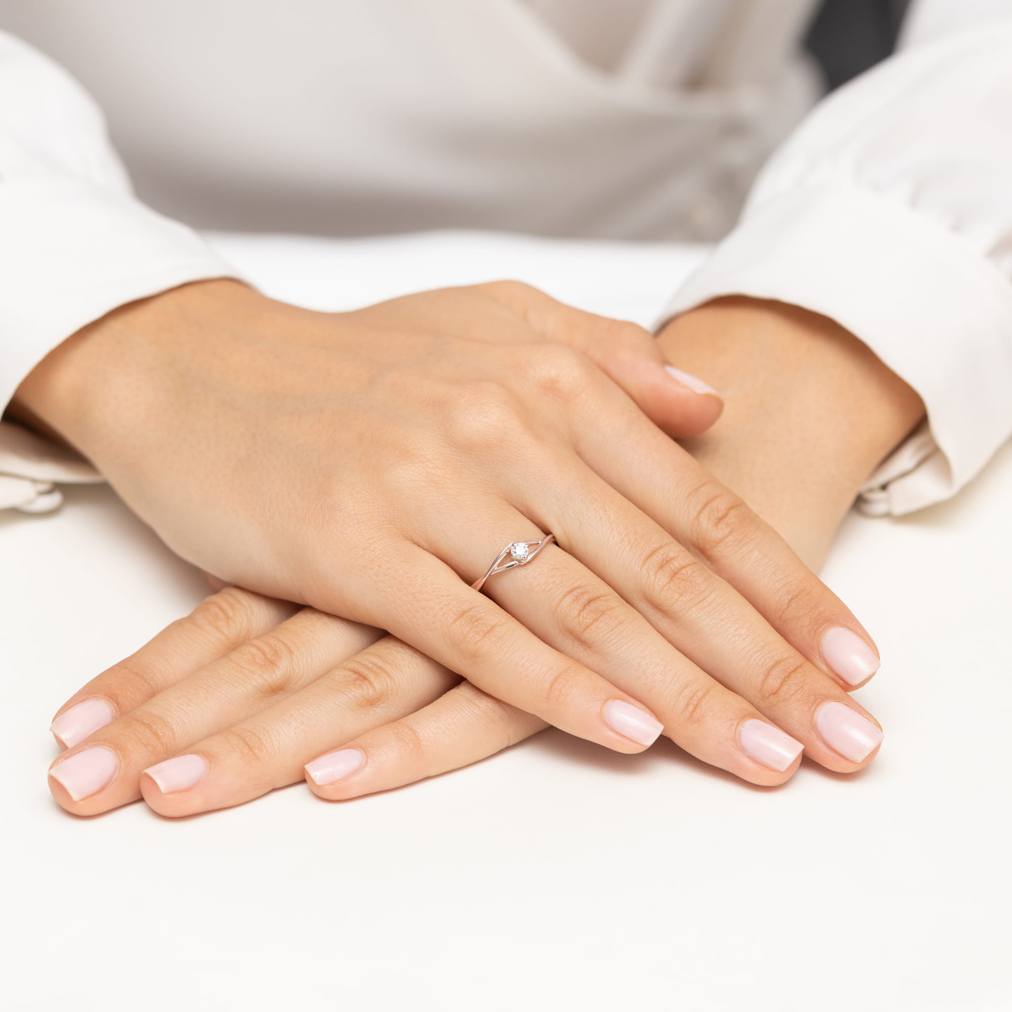 W0669.R3.DIW.01_4 Dwie dłonie z delikatnym pierścionkiem na palcu, z zadbanymi paznokciami w jasnym kolorze.