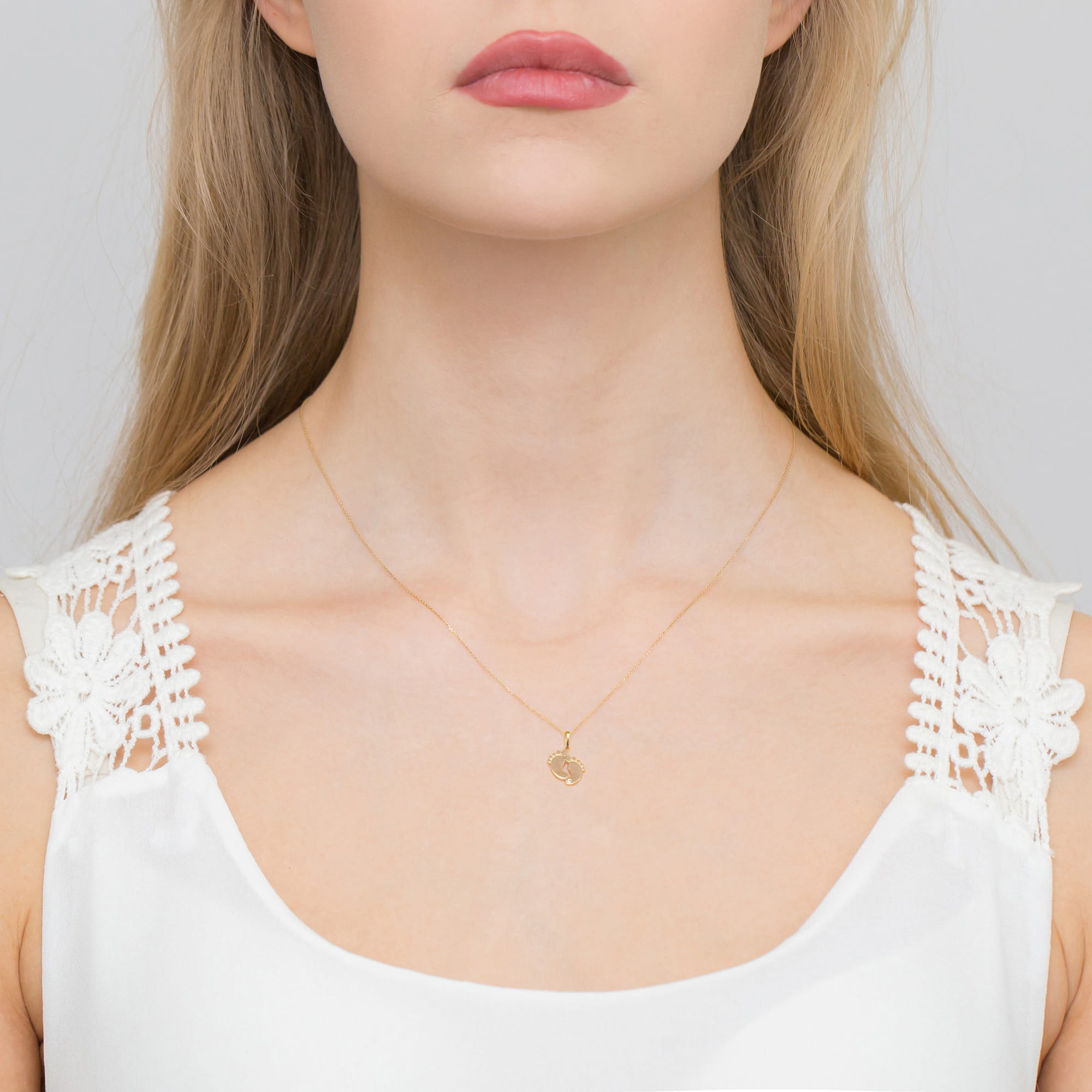 Z0033.Z3.DIW.01_2 Kobieta z długimi, jasnymi włosami, nosząca złoty naszyjnik w kształcie serca, w białej bluzce z koronkowymi detalami.